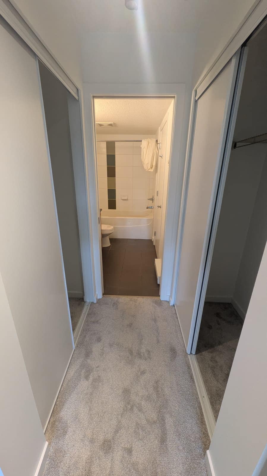 1. Bright bathroom with bathtub and neutral decor, accessible from bedroom walk-in closet in a modern condo.