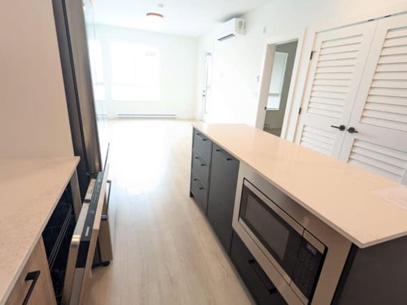 Bright modern kitchen with stainless steel appliances, white countertops, and light wood flooring, perfect for Vancouver-area homes.