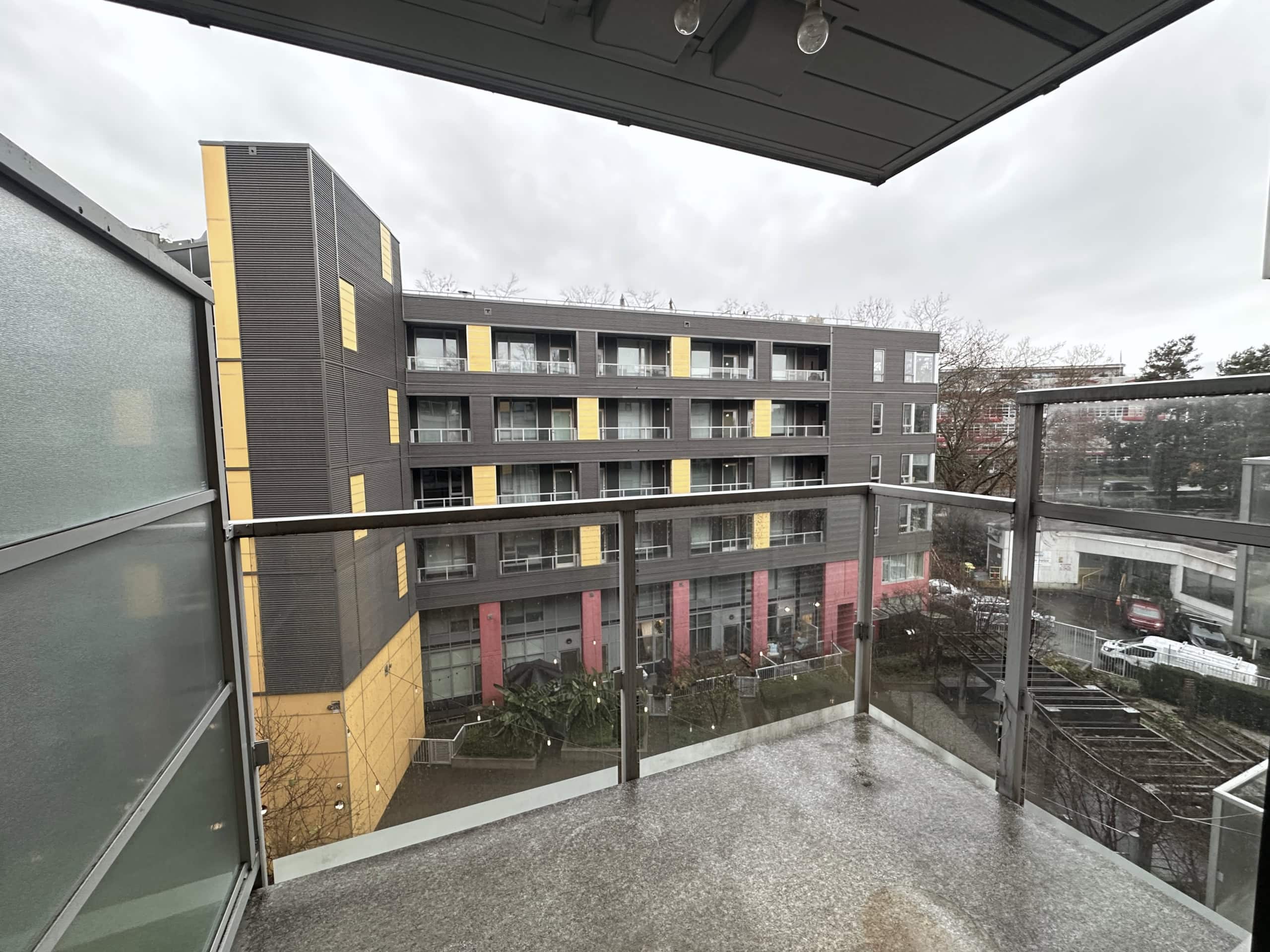 Modern city view from a balcony in a contemporary apartment building, showcasingurban living in Vancouver, BC with sleek architecture and vibrant accents.