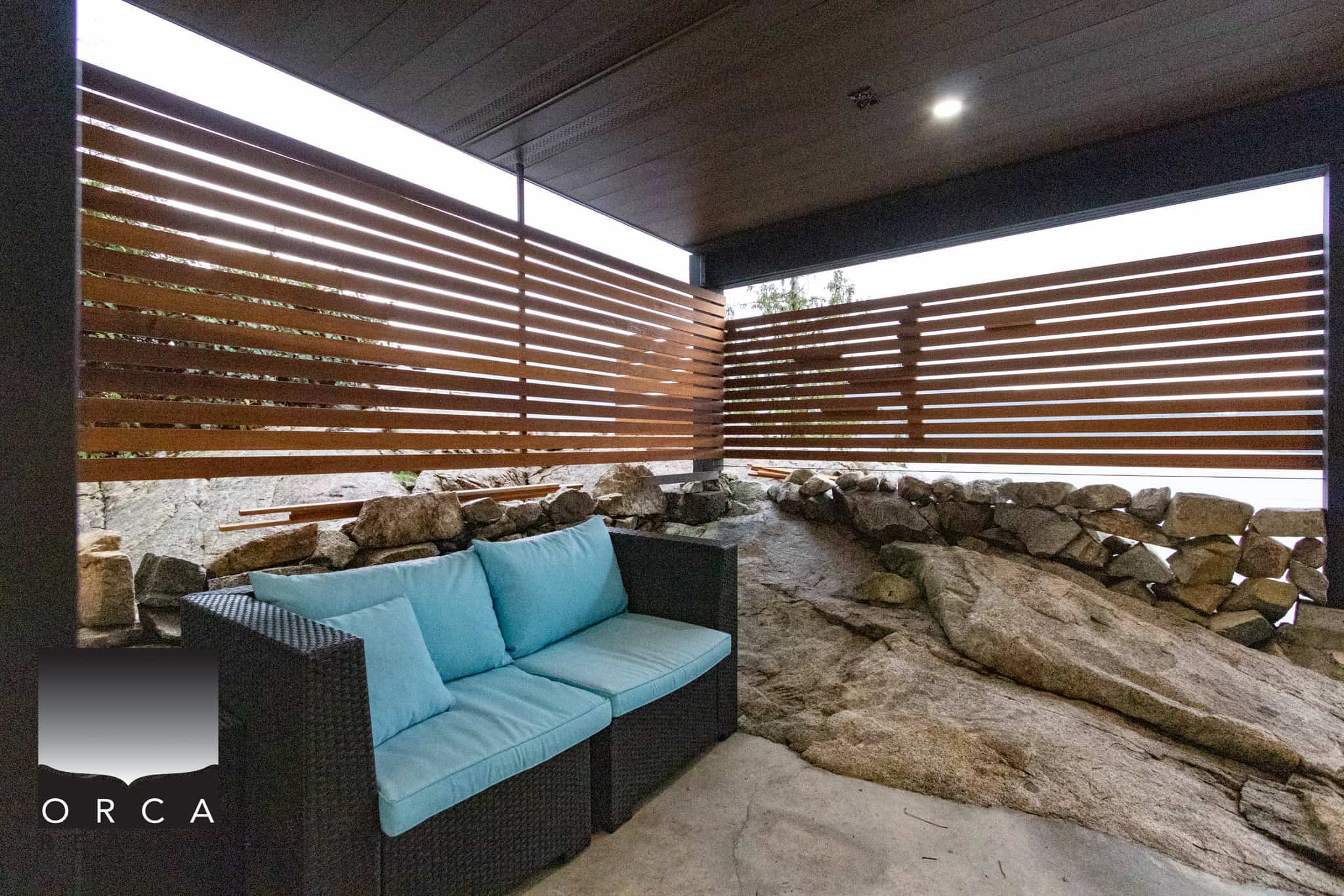 Bright outdoor patio space with modern privacy wooden slat fencing, natural stone accents, and comfortable seating, perfect for relaxation and entertaining in Vancouver real estate.
