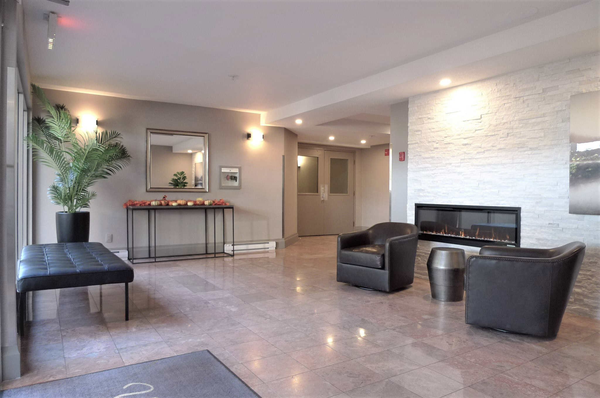 Modern condo lobby with stylish black lounge chairs, contemporary fireplace, and elegant decor, showcasing Orca Realty's expertise in Vancouver Island real estate.