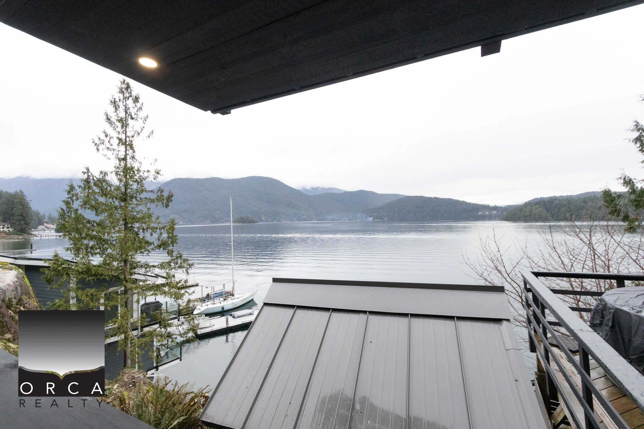 1. Breathtaking waterfront view from a Vancouver Island oceanfront property with mountains, trees, and boats.