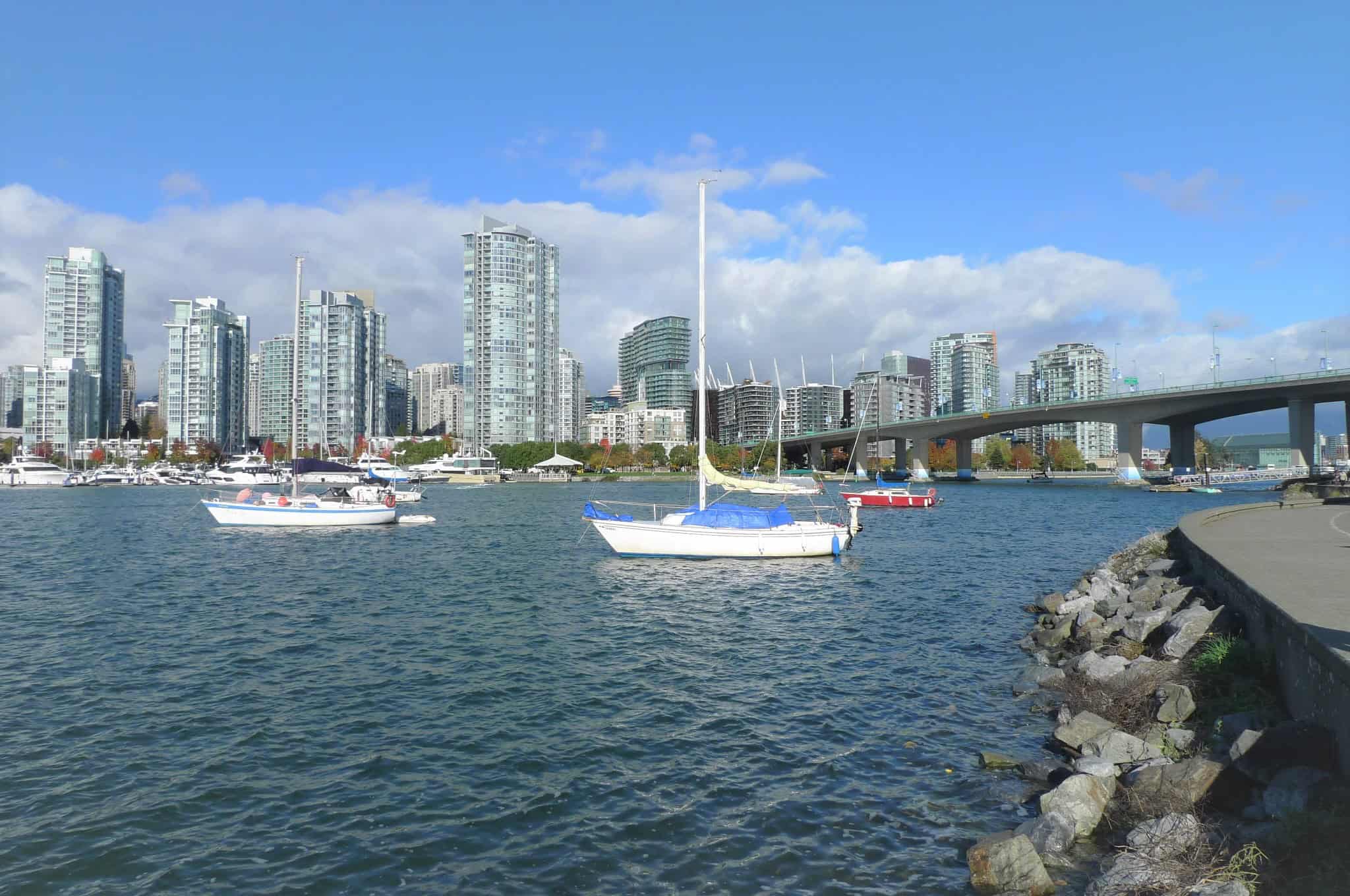 Vibrant Vancouver waterfront with sailboats and modern high-rise condos, showcasing Orca Realty Inc.'s prime real estate opportunities in the city’s scenic harbor.