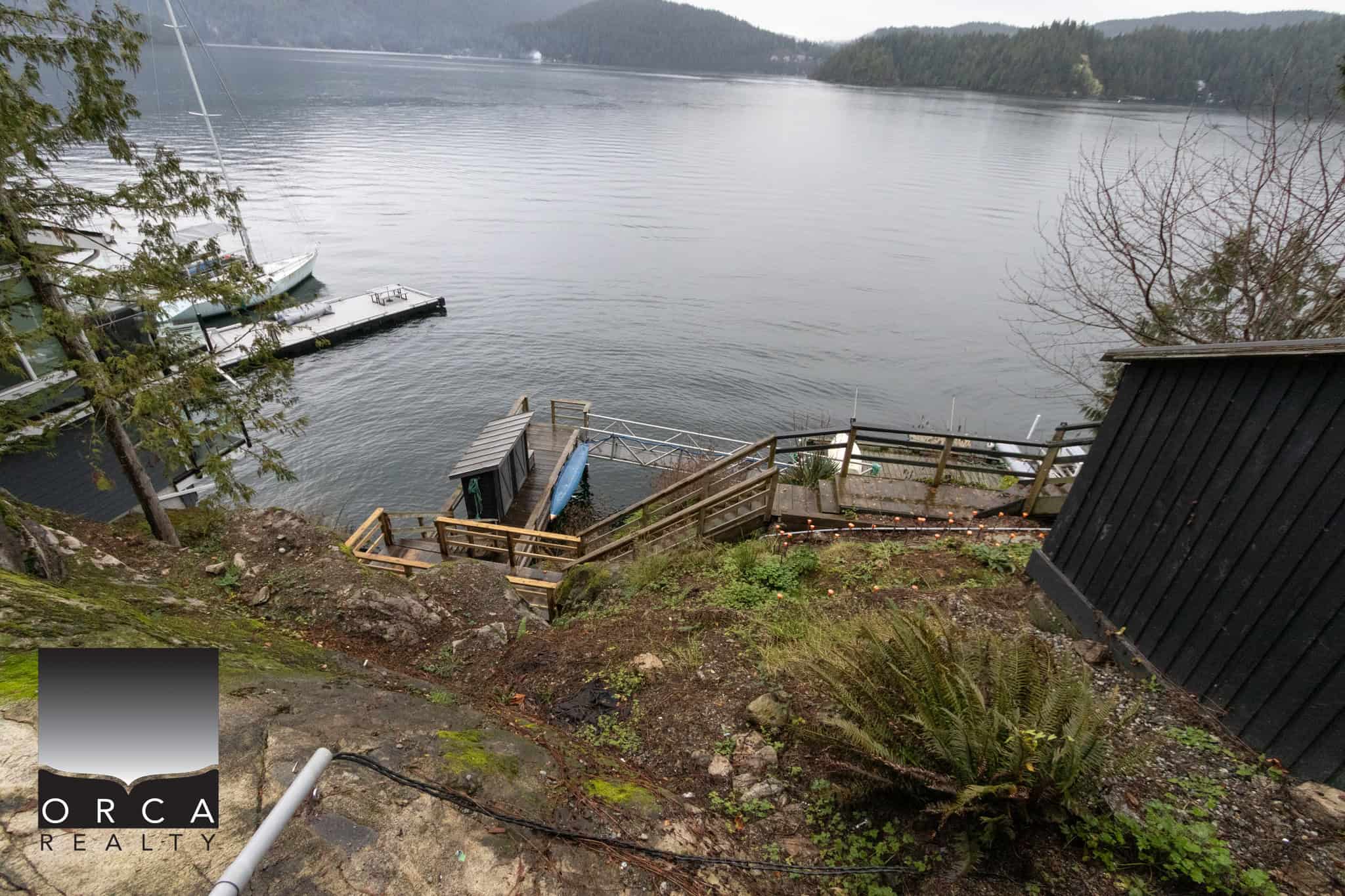 Stunning waterfront view with boat dock and scenic water access, showcasing prime real estate opportunities on Vancouver Island, BC. Perfect for waterfront property buyers seeking tranquility and natural beauty.