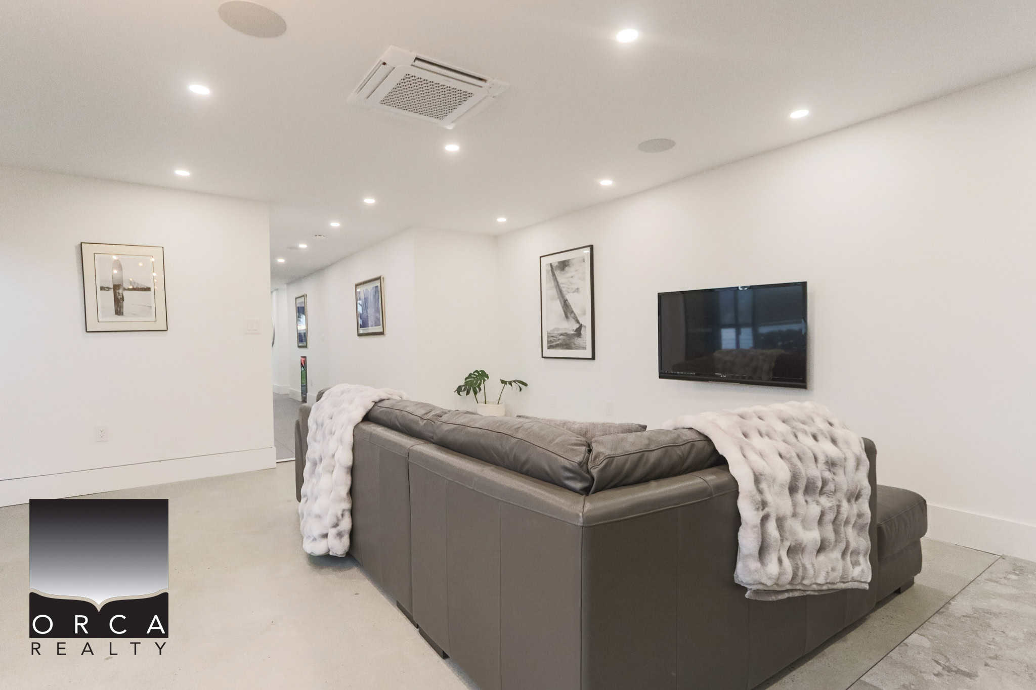 Modern interior living room with white walls, ceiling-mounted lights, wall-mounted TV, and stylish decor, showcasing an inviting space for relaxation with contemporary furnishings.
