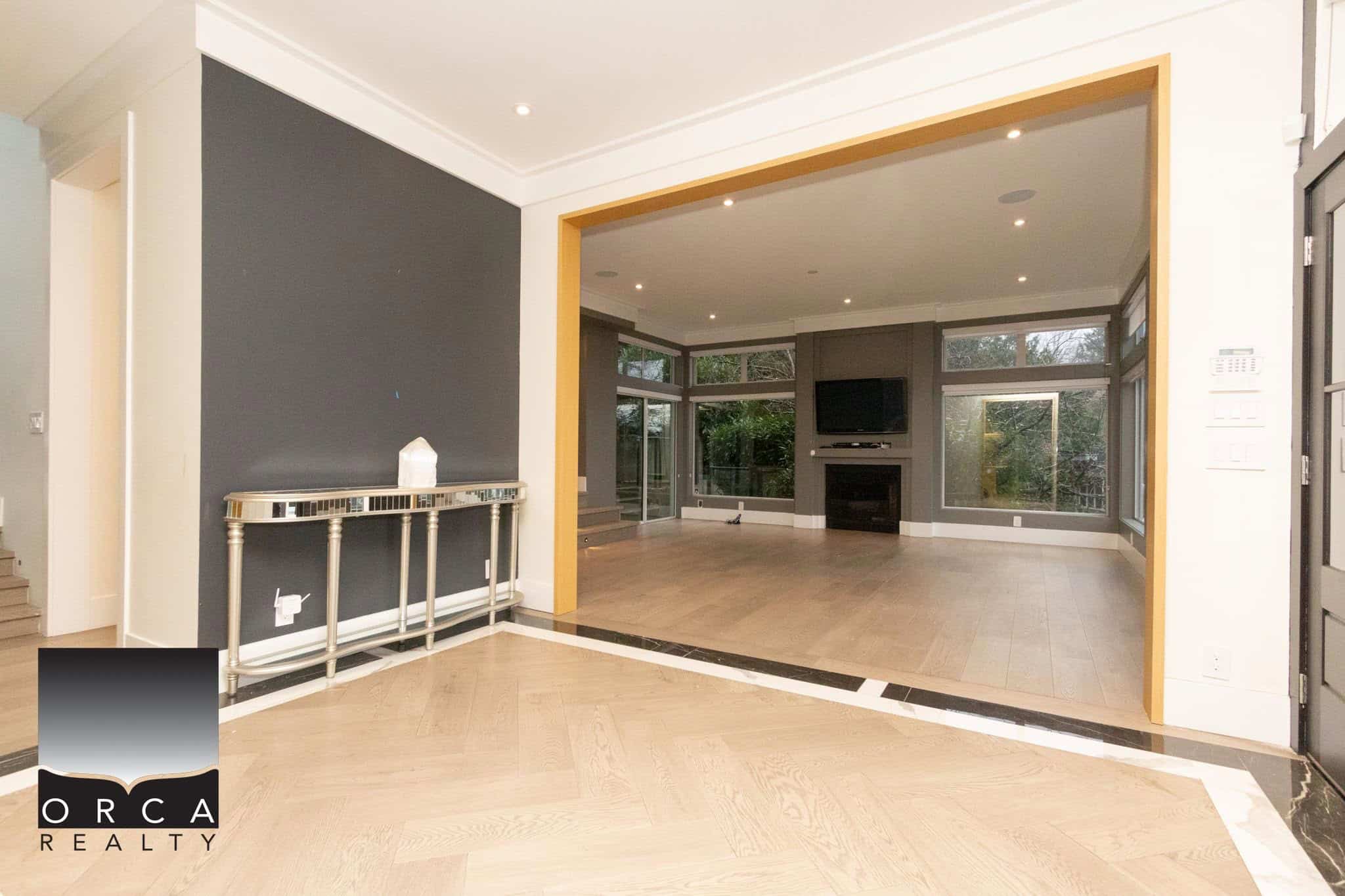 Bright, modern living room with large windows, hardwood floors, fireplace, and contemporary interior design showcasing Orca Realty Inc. property listings in Canada.