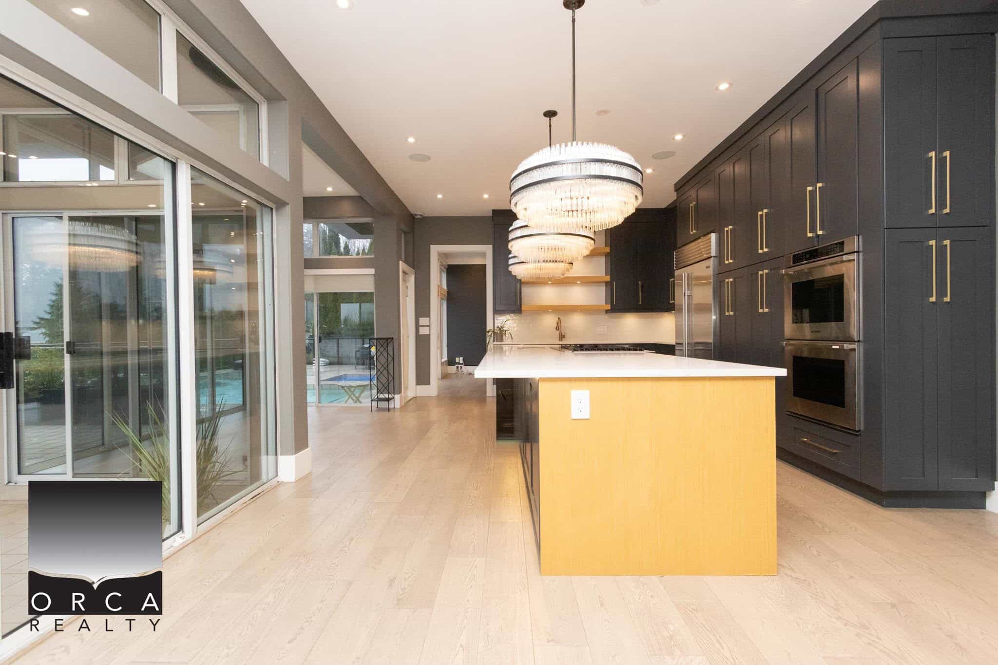 Modern kitchen with black cabinetry, white countertops, and elegant pendant lighting, offering a luxurious Vancouver Island real estate experience.