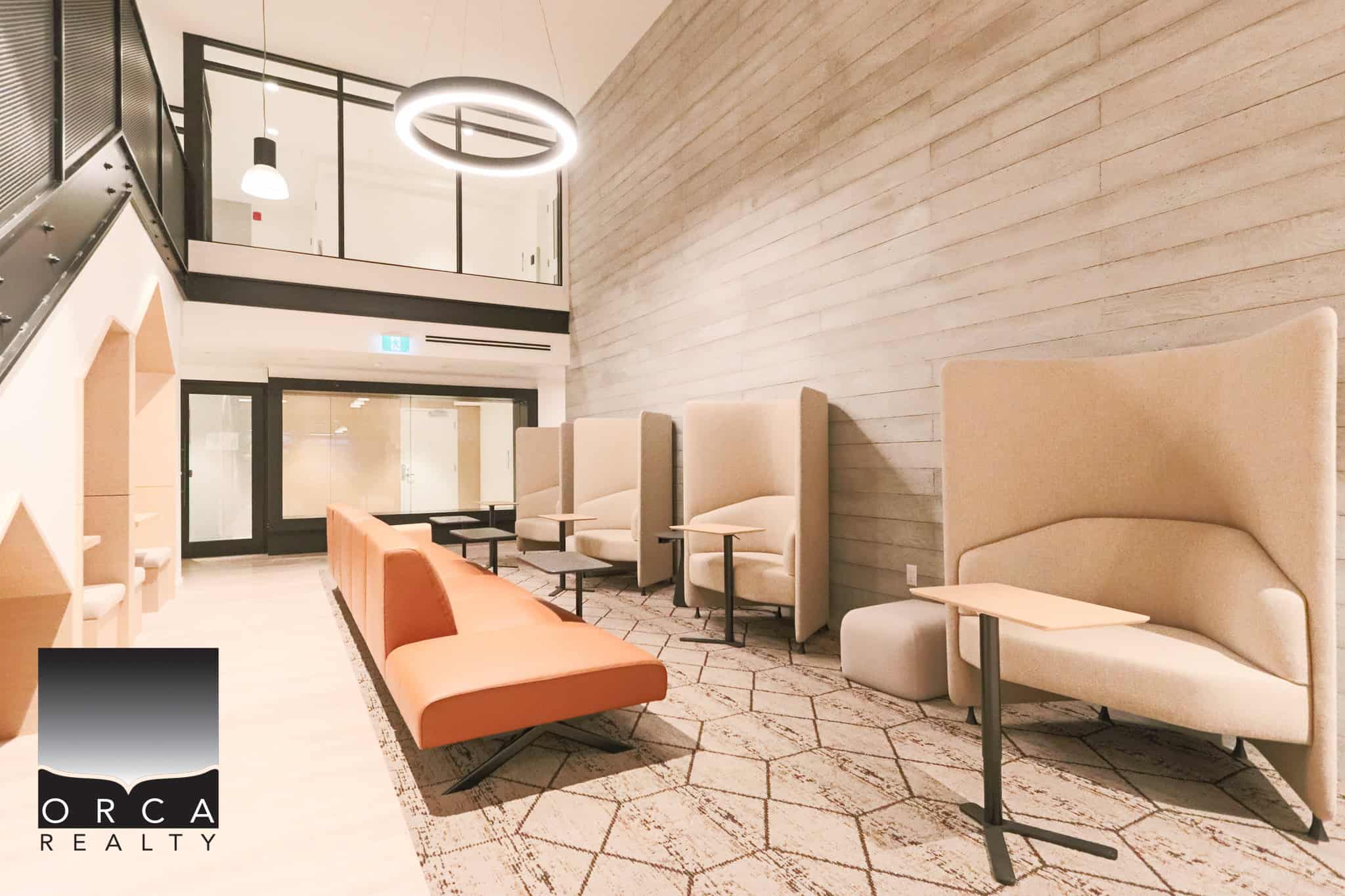 Modern lobby area at Orca Realty Inc. office with contemporary seating, high ceilings, and stylish decor, perfect for client meetings and comfortable waiting in a professional real estate environment.