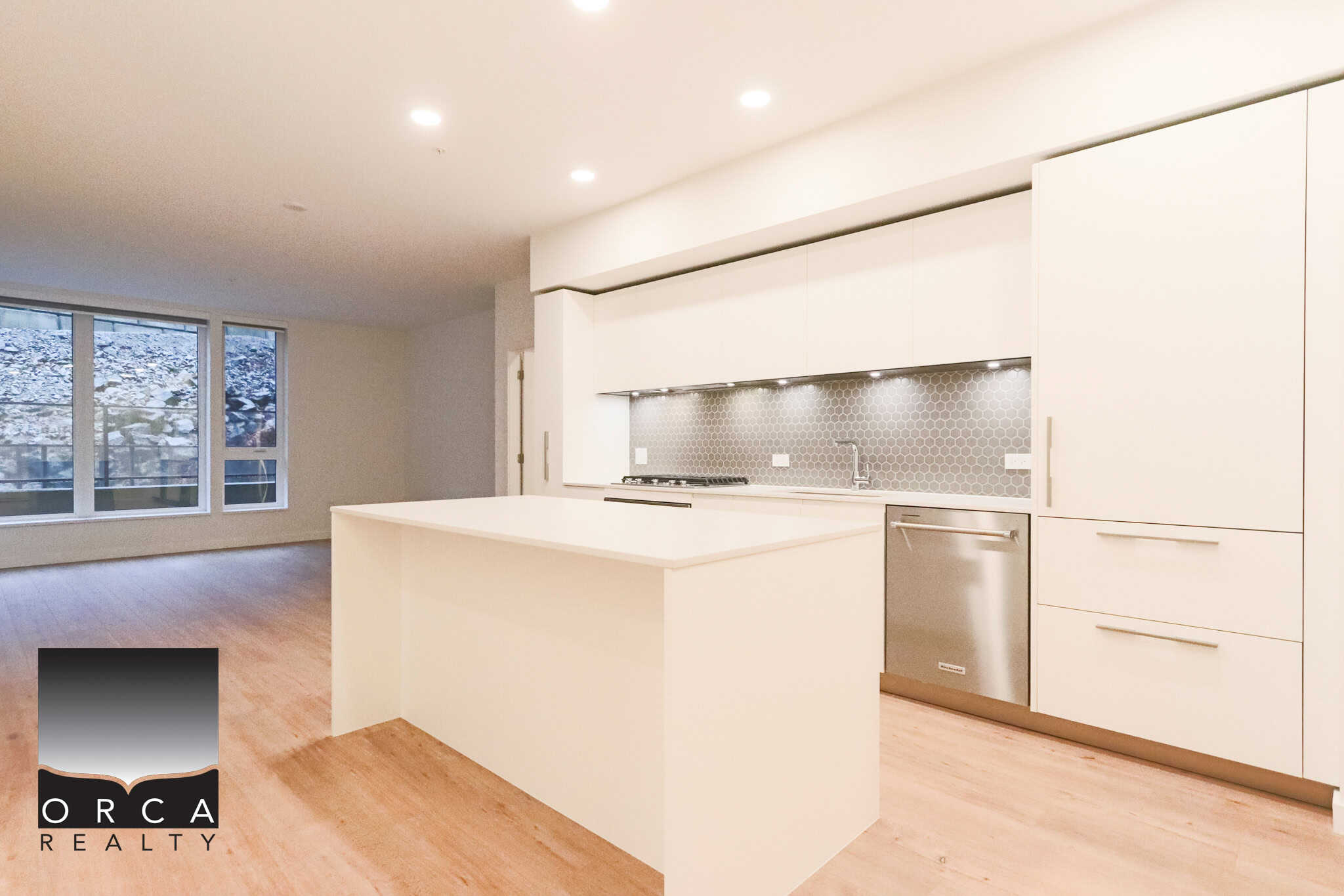 Modern bright kitchen with white cabinetry, stainless steel appliances, quartz countertops, and a unique gray tile backsplash in a contemporary residential property.