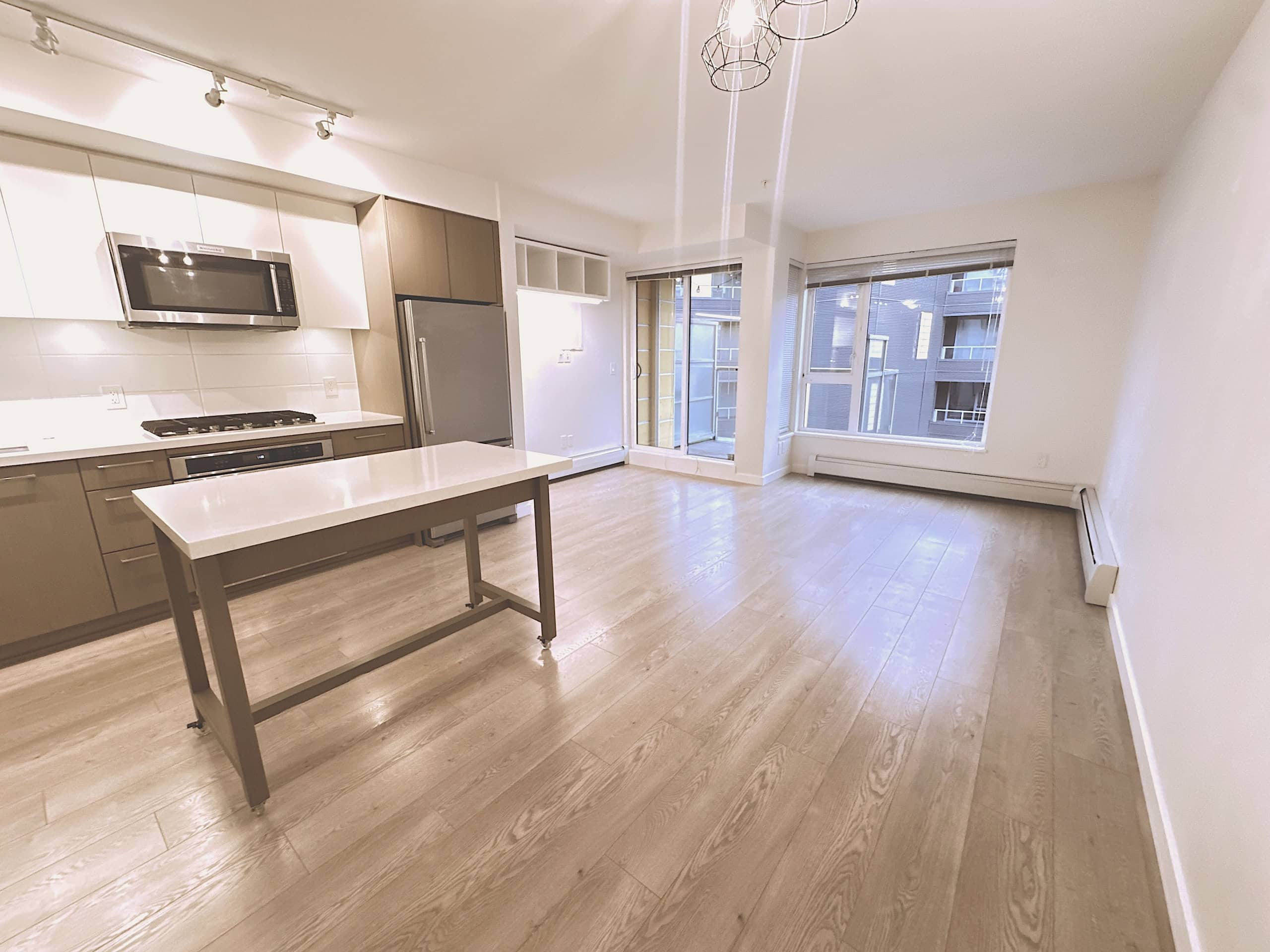 Spacious modern open-concept apartment with kitchen, large windows, and bright natural light, ideal for comfortable living in a vibrant urban community in Vancouver.