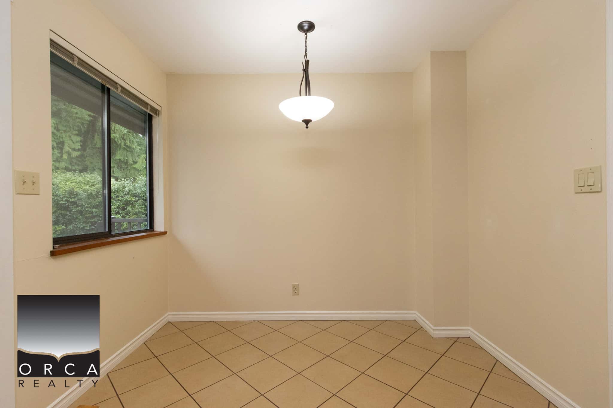 Bright empty dining room with large window, beige wall colour, and tiled floor, ideal for Vancouver home staging, real estate sales, and property showcasing when selling or renting.
