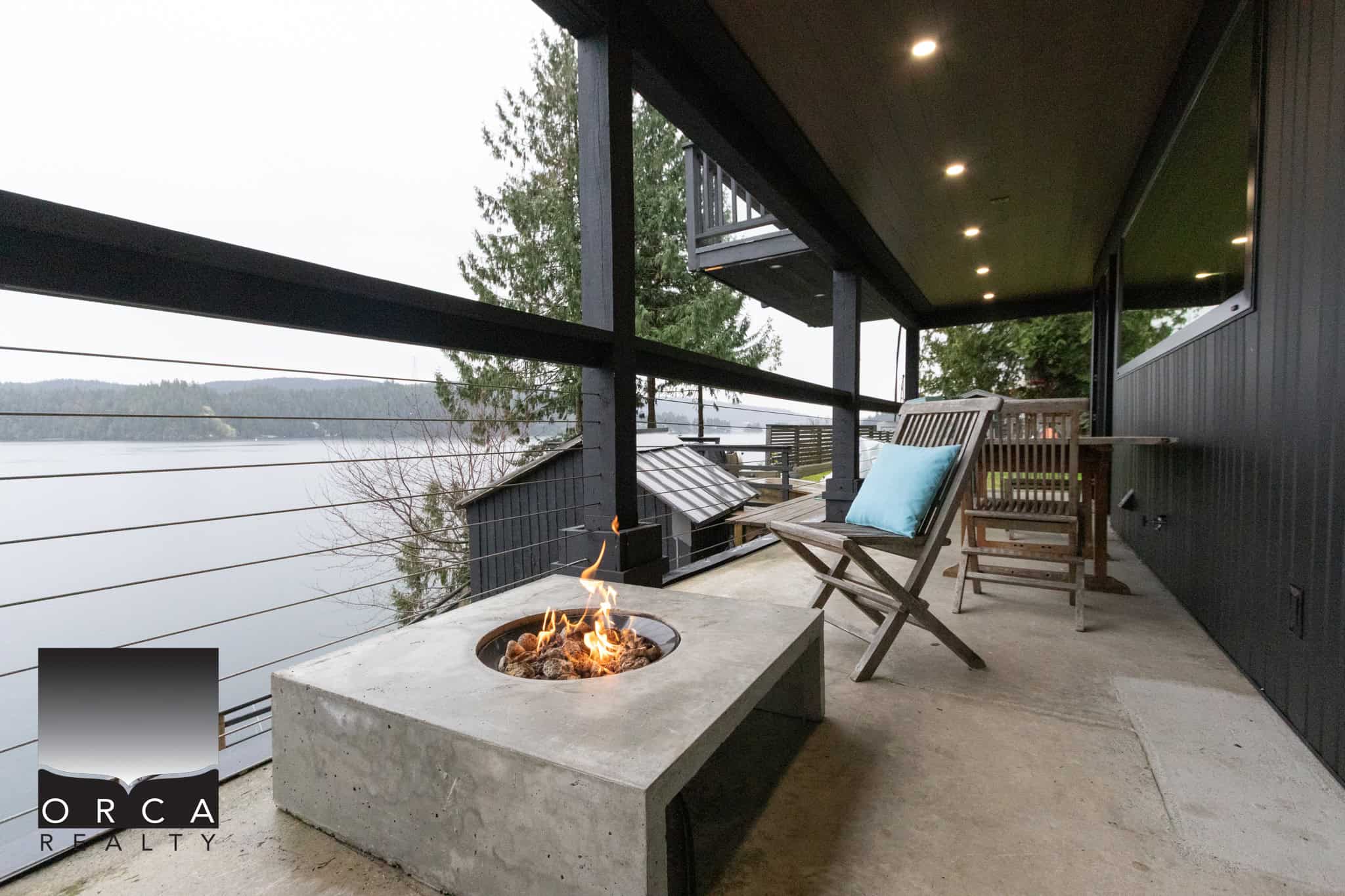 Stunning waterfront balcony with modern fire pit, cozy seating and scenic views, perfect for relaxing and entertaining in Vancouver’s real estate market.