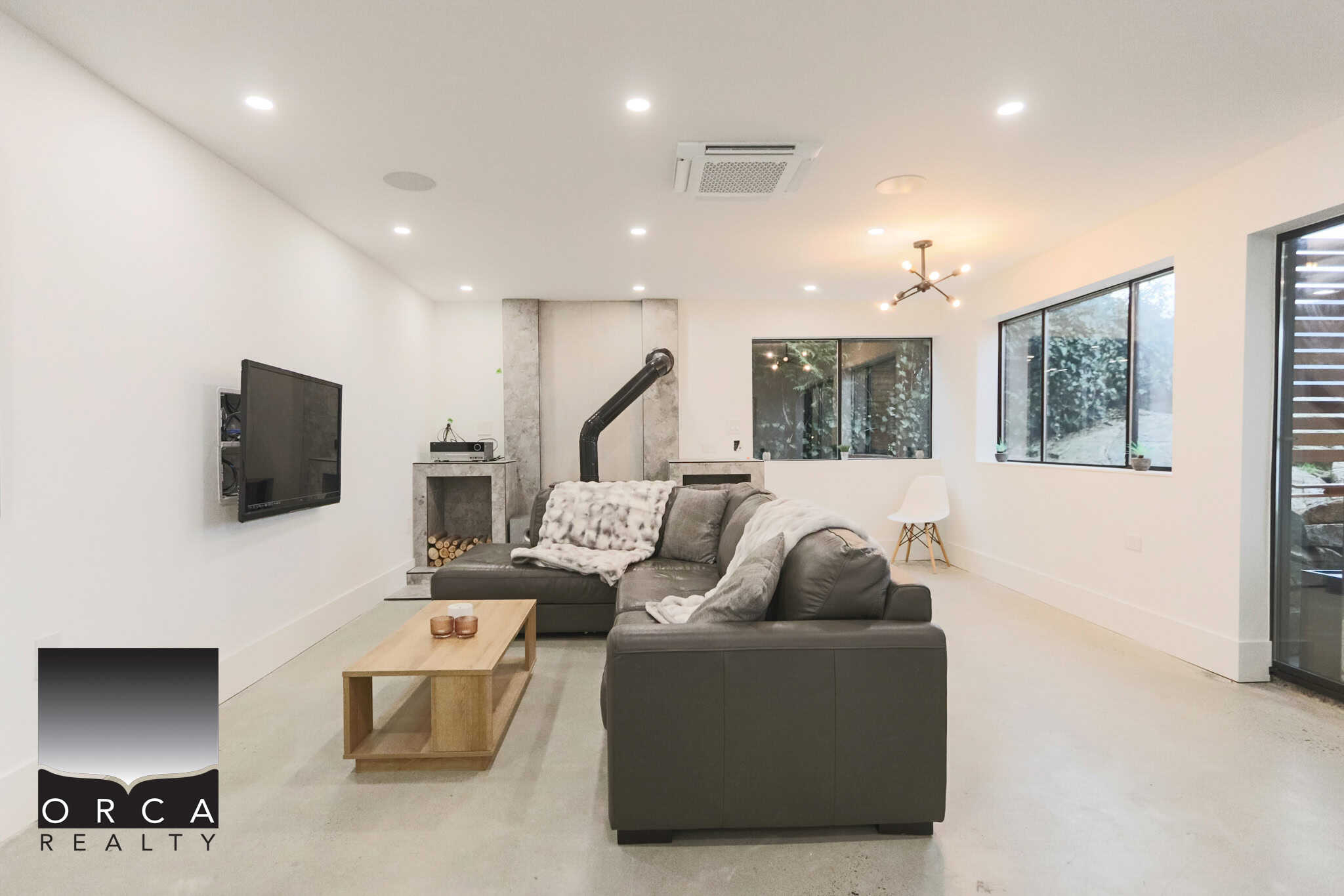 Modern living room with contemporary furnishings, large windows, and stylish lighting, perfect for Vancouver Island real estate buyers seeking spacious, light-filled homes.