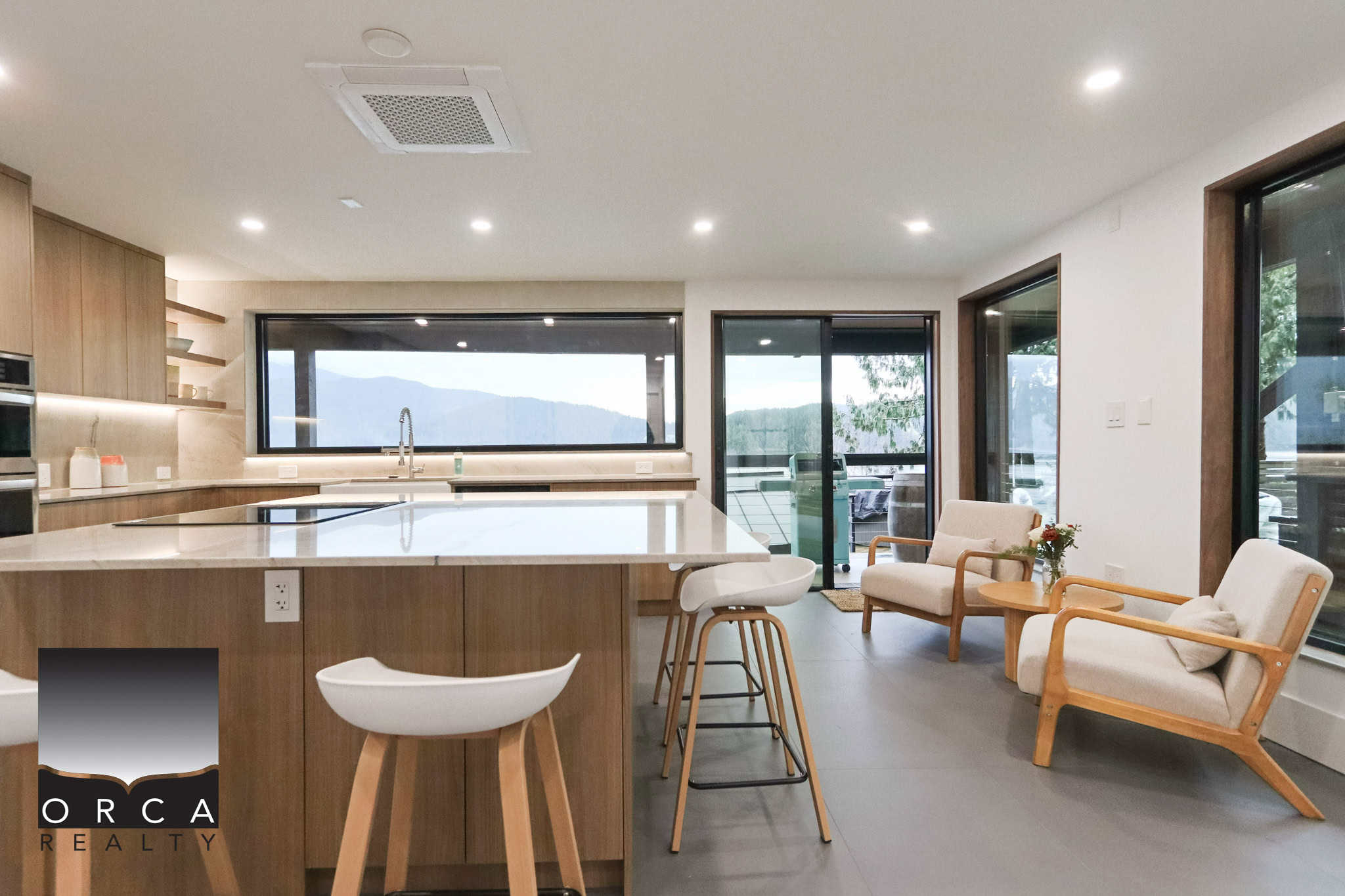 Modern Vancouver Island kitchen with open-concept living space, large windows, and mountain views, ideal for real estate listings and showcasing home features by Orca Realty Inc.