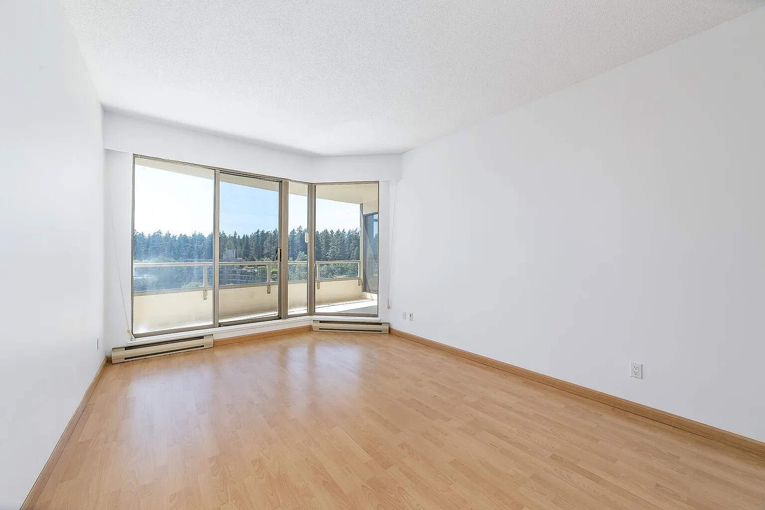 Bright empty living room with large sliding glass doors leading to balcony, natural light, hardwood floors, modern interior, ideal for Vancouver real estate, in Orca Realty Inc. listings.