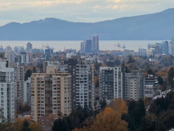 Vancouver city skyline with water view, residential buildings, and mountain backdrop in autumn, showcasing real estate opportunities in Vancouver, BC.