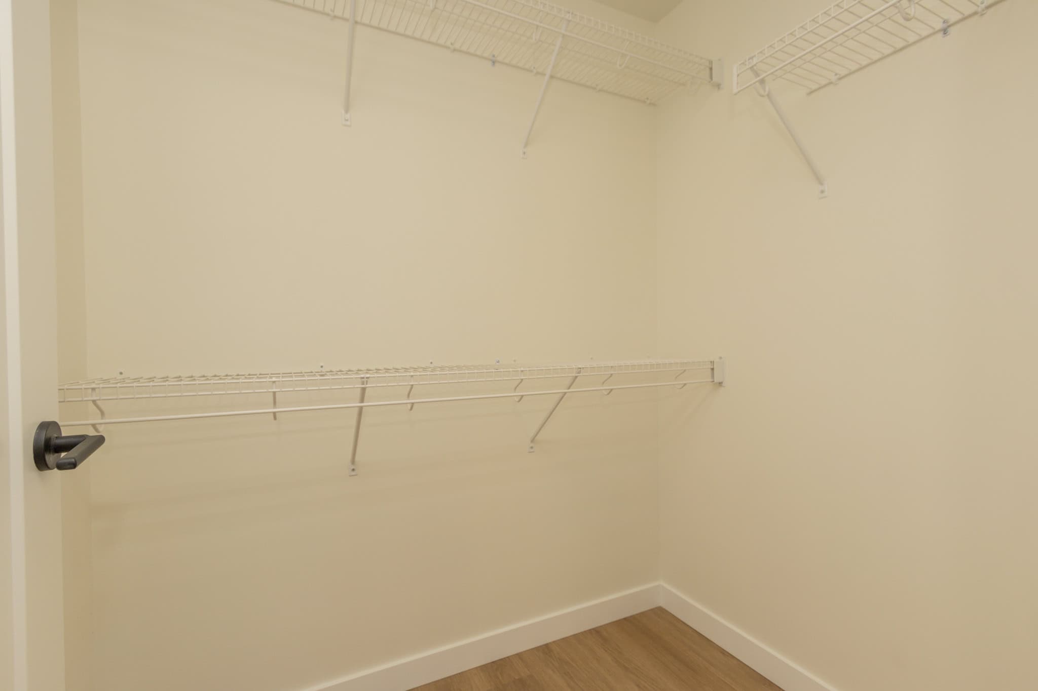 Spacious walk-in closet with white wire shelving unit, ideal for organized storage in a modern home or condo, perfect for Vancouver area real estate listings.