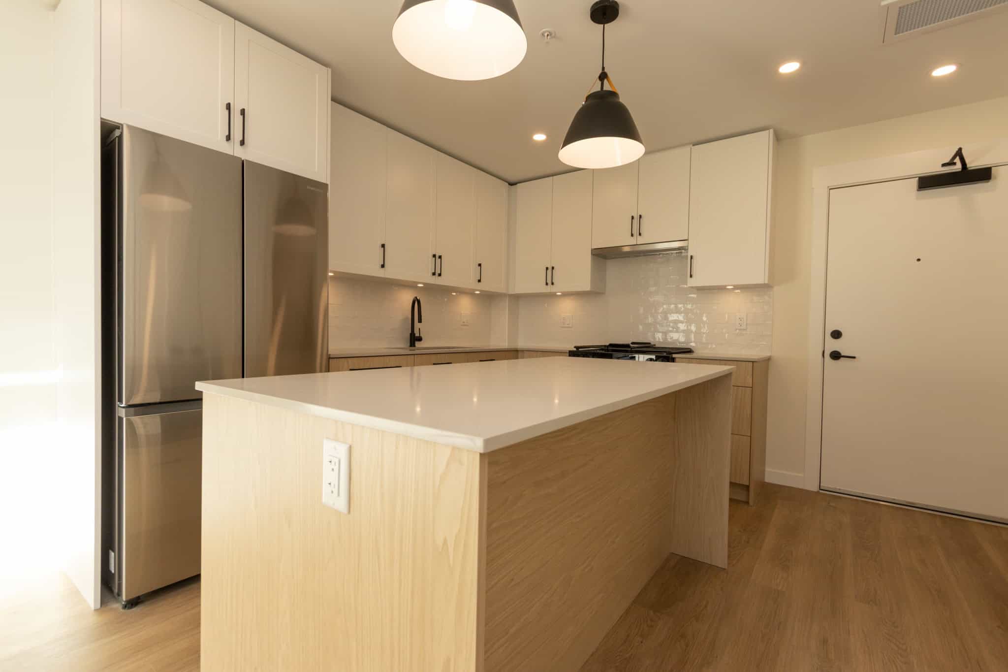 Stylish modern kitchen with white cabinetry, stainless steel appliances, and a spacious island, perfect for urban living and home entertaining in Vancouver.