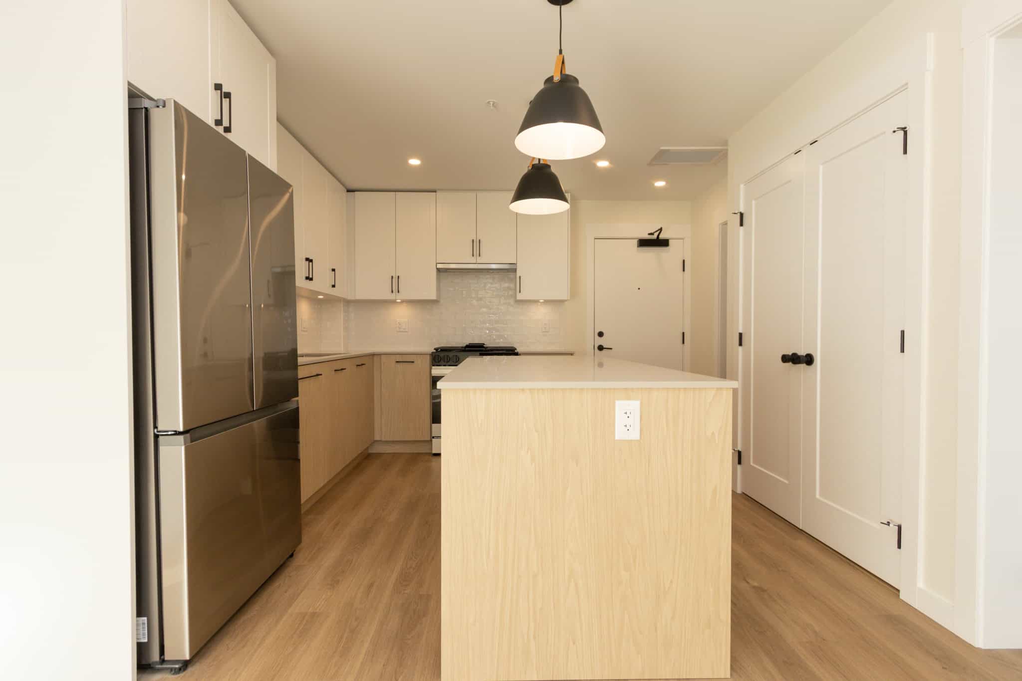 Modern open-concept kitchen with white cabinets, stainless steel appliances, and a wooden island, perfect for family living and entertaining in Vancouver.