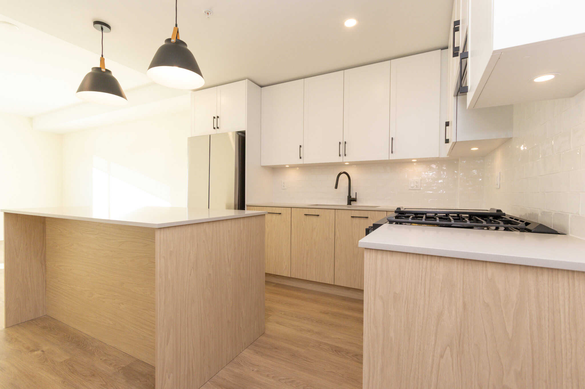 Modern kitchen interior with white cabinets, black hardware, and natural wood accents, perfect for homebuyers seeking contemporary residential properties in Vancouver.