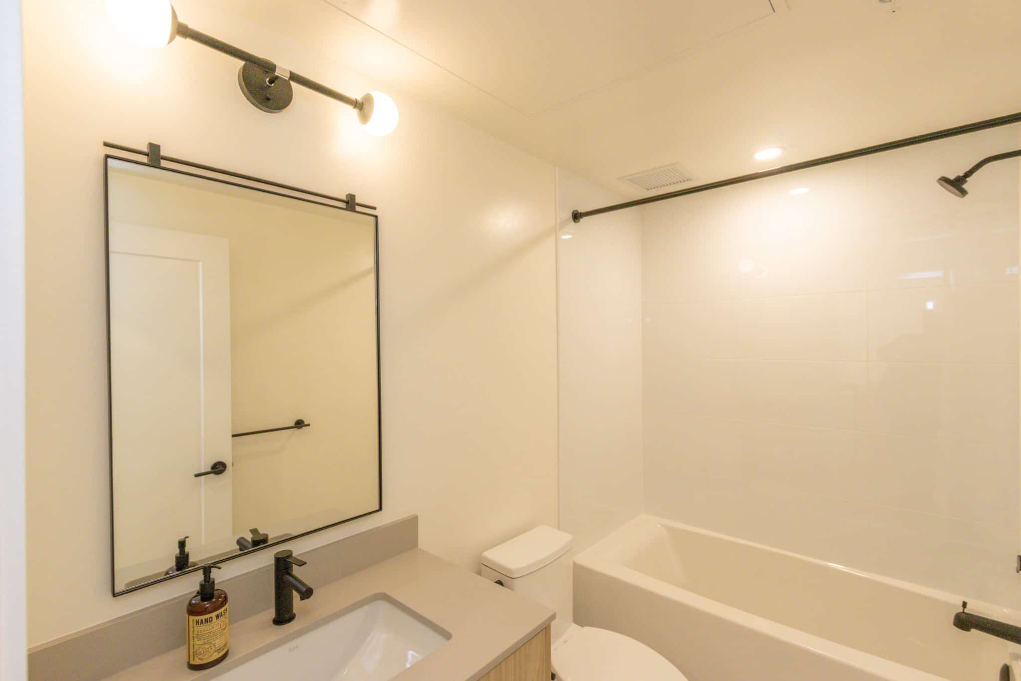 Modern bathroom featuring sleek design, white tiles, black fixtures, and a walk-in shower with a contemporary black shower head; ideal for stylish home living.