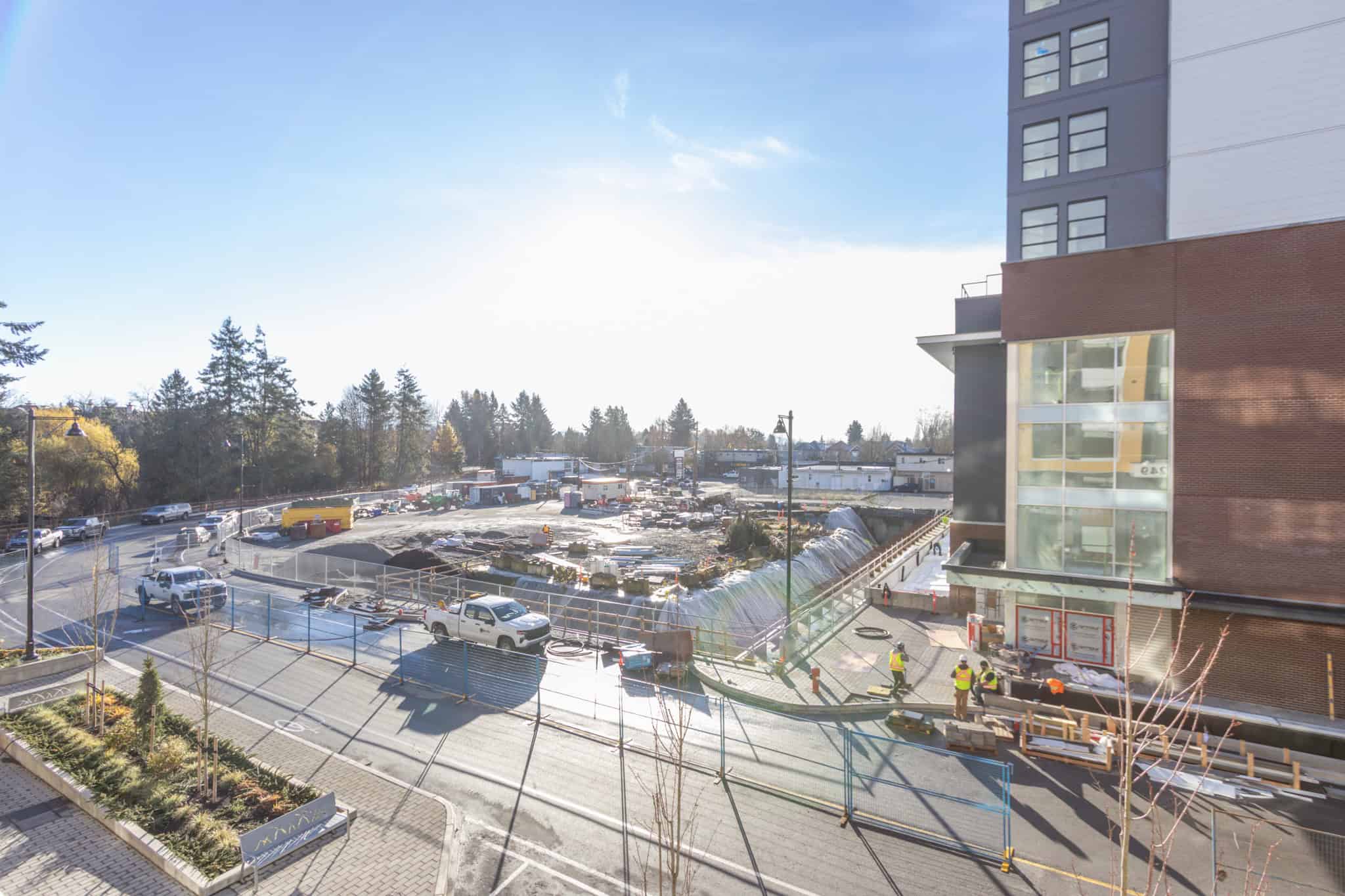 Construction site view of modern residential building with ongoing development, outdoor parking, and surrounding greenery, highlighting real estate development in Vancouver, BC.