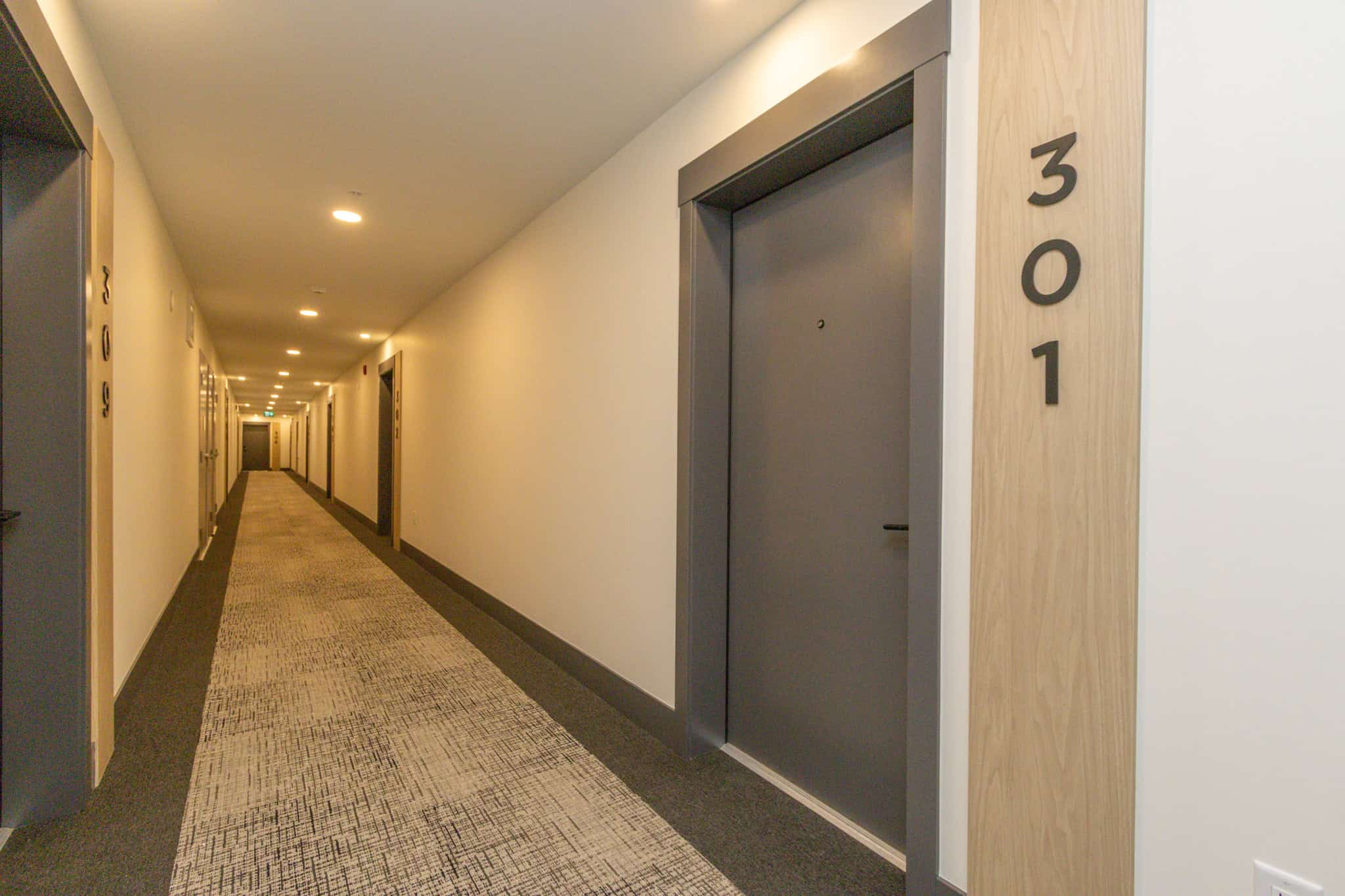 Modern apartment building hallway with contemporary elevator, clean design, and stylish wood accents, showcasing professional property management by Orca Realty Inc. in BC.