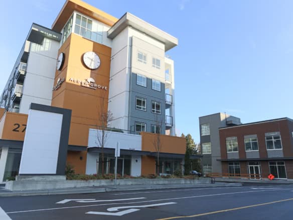 Modern condo building in Aldergrove with contemporary architecture, large windows, and a clock tower, offering prime real estate and residential living opportunities in Langley, BC.