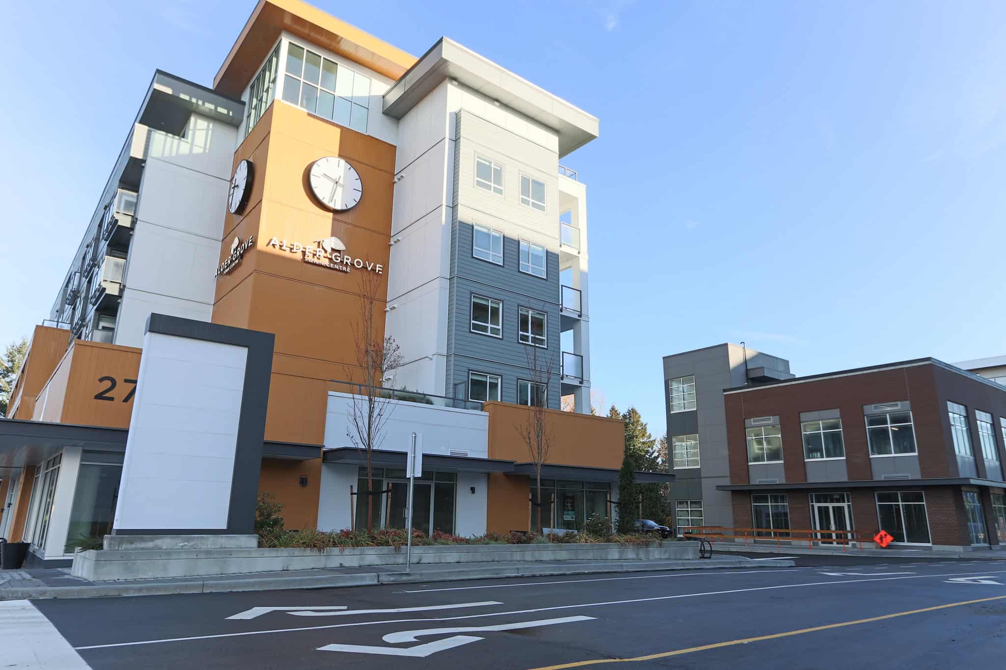 Modern condo building in Aldergrove with contemporary architecture, large windows, and a clock tower, offering prime real estate and residential living opportunities in Langley, BC.