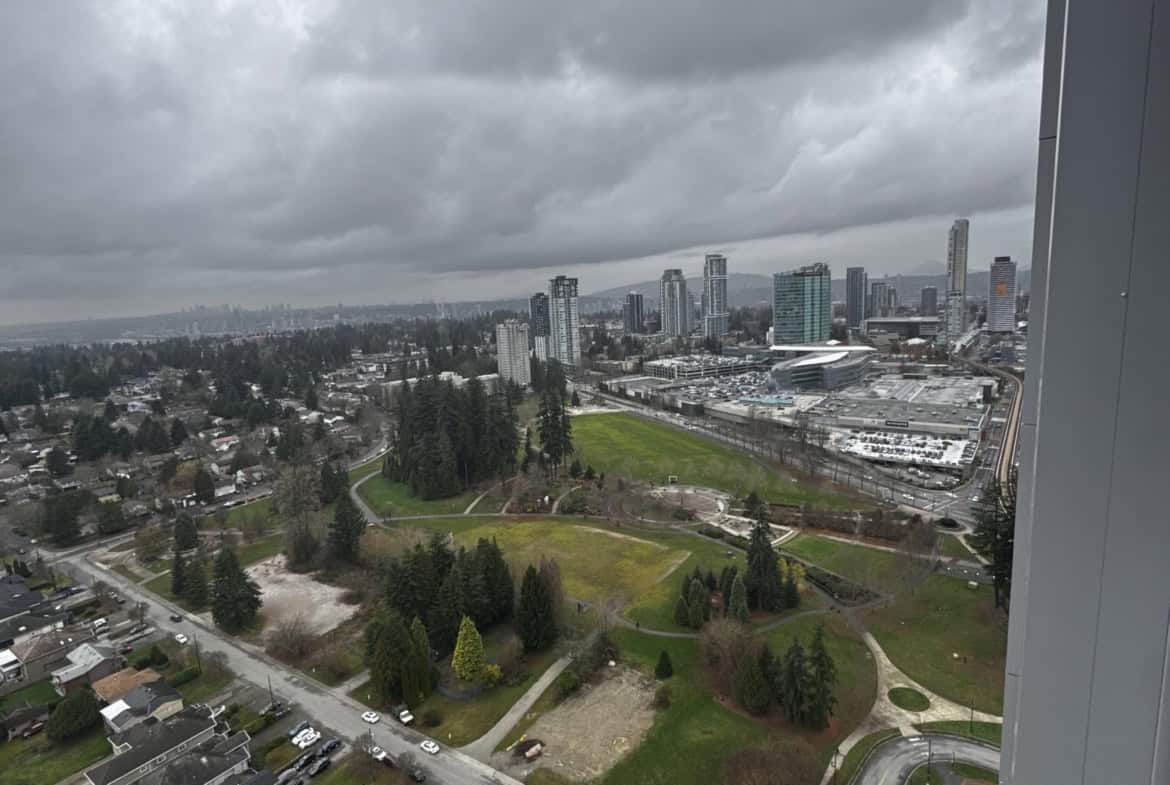 Panoramic view of Vancouver skyline and city parks from high-rise residential building on a cloudy day, showcasing real estate and property development in BC.