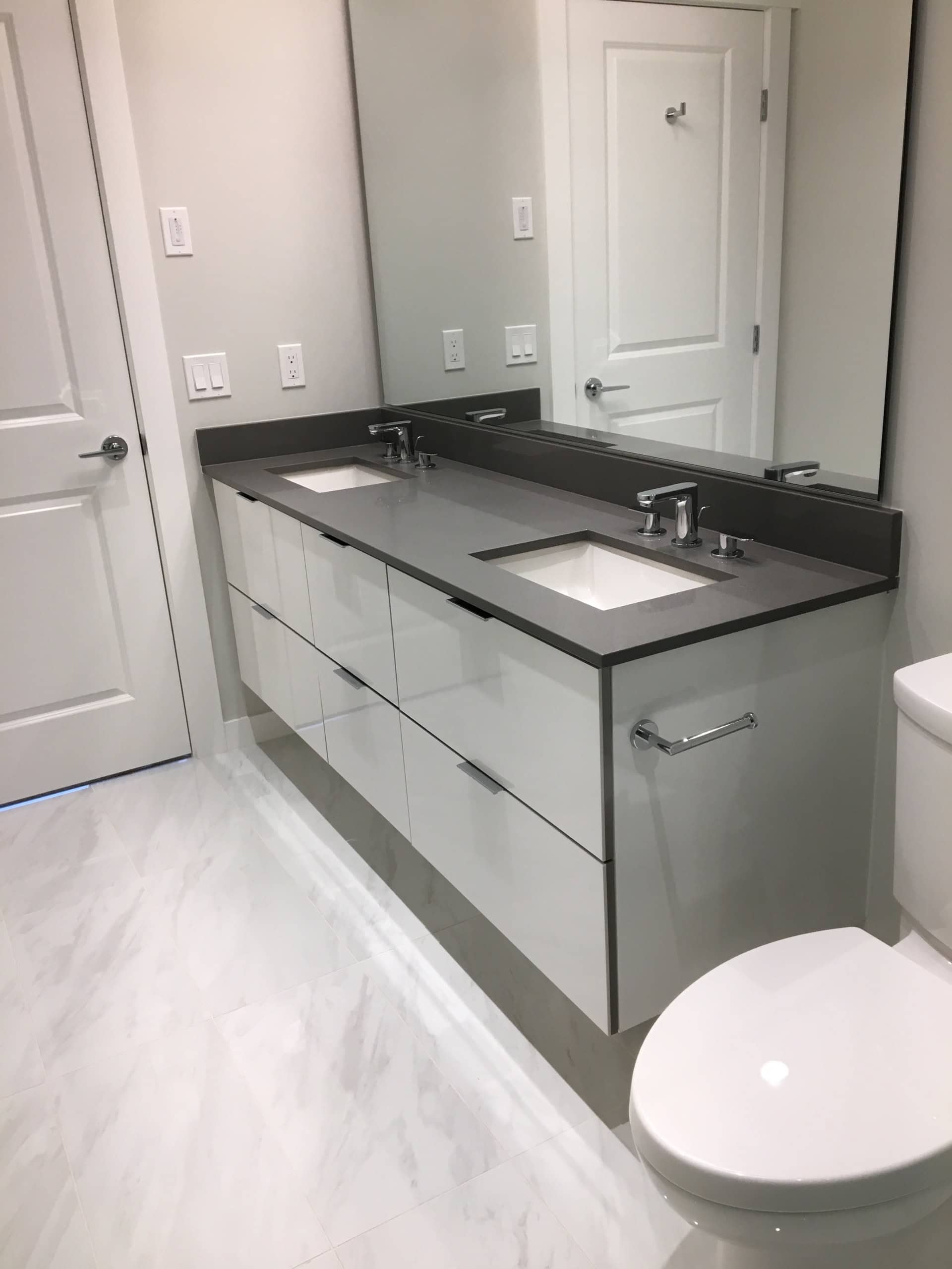 Modern bathroom vanity with dual sinks, large mirror, white cabinetry, and neutral colour palette, showcasing contemporary interior design in a residential space.