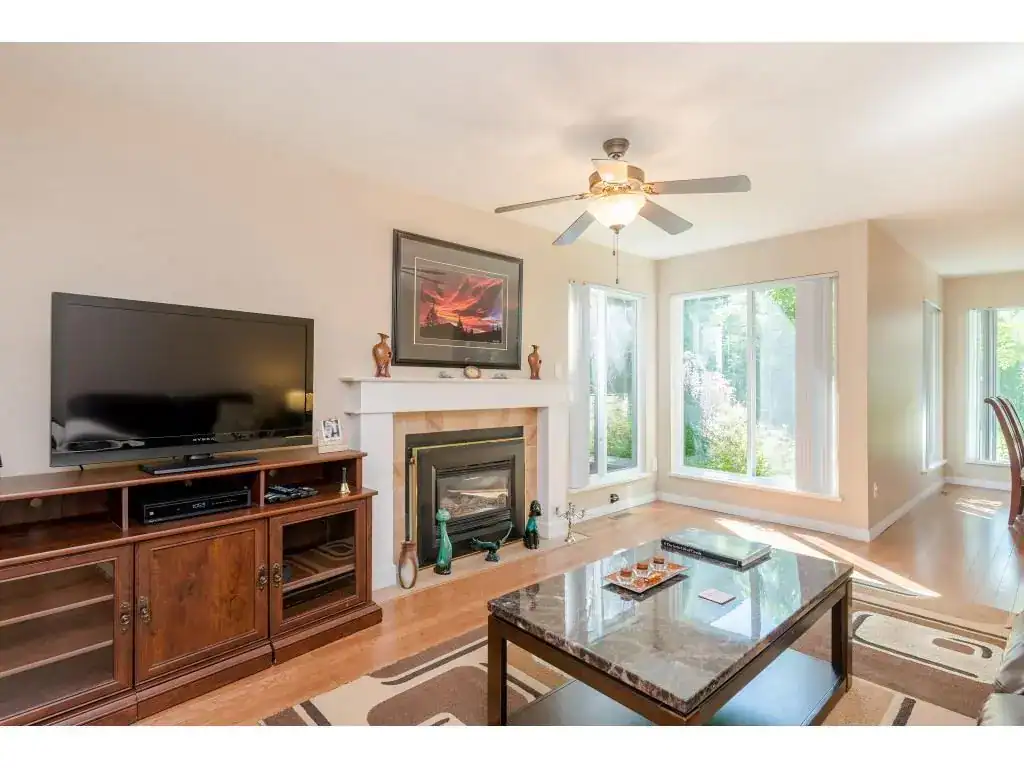 Bright living room with large windows, fireplace, and modern decor, showcasing a cozy and inviting home environment perfect for family living and relaxation.