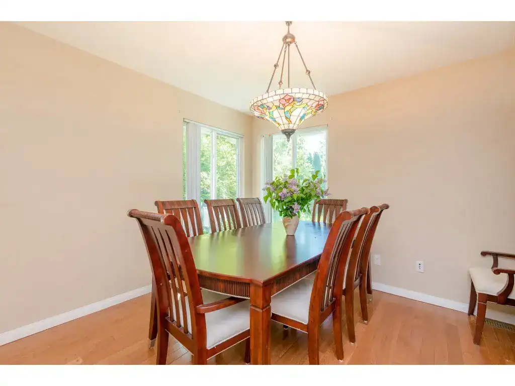 Bright dining room with large windows, wooden table, and elegant chandelier, perfect for family gatherings and entertaining in Vancouver homes.