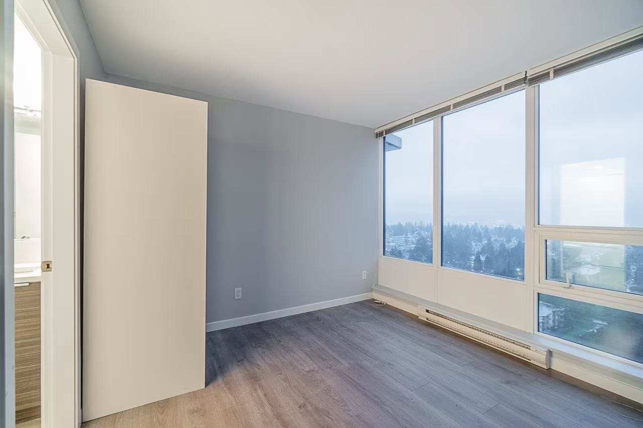 image9 Bright, modern condo room with large windows showcasing city and mountain views, featuring updated flooring and fresh paint, perfect for Vancouver real estate buyers and investors.