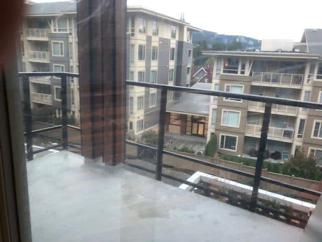 Bright balcony view near modern residential buildings in Vancouver, BC, showcasing urban living and scenic mountain backdrop. Ideal for real estate listings and property marketing.