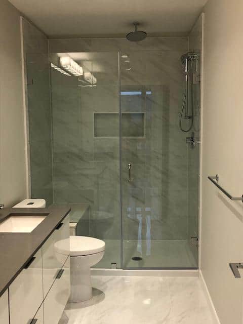 Modern glass-enclosed walk-in shower with sleek marble tiles in a contemporary bathroom | Orca Realty Inc.
