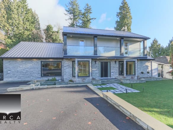 Modern luxury home with contemporary design, stone exterior, large windows, and balcony — ideal for Vancouver Island real estate and waterfront property buyers in BC.