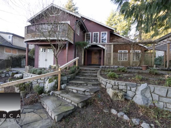 Charming Vancouver Island-style home with lush gardens, stone pathways, and ocean views, perfect for buyers seeking waterfront properties and coastal real estate in British Columbia.