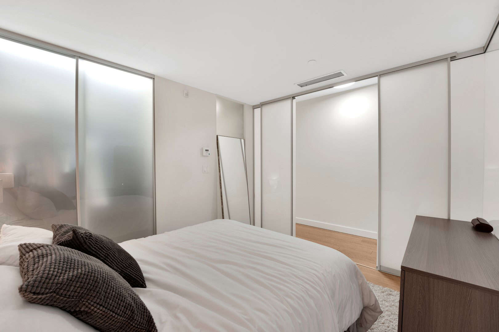 10 Modern bedroom with sleek frosted glass closet doors, minimalist decor, and neutral tones, showcasing Vancouver-area real estate expertise by Orca Realty Inc.