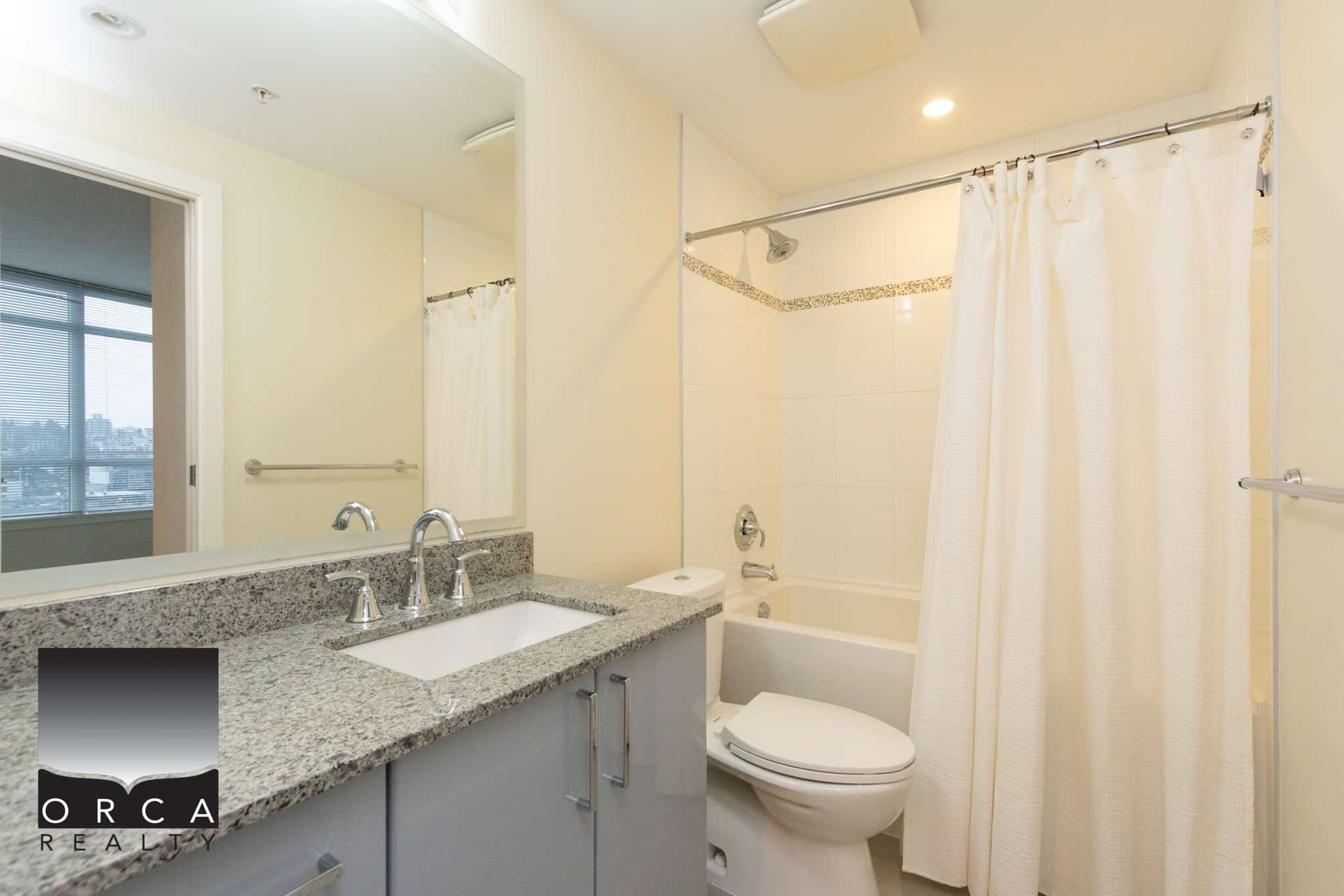 10 (3) Bright modern bathroom with a granite countertop vanity, shower and bathtub, in a contemporary apartment listing by Orca Realty Inc.