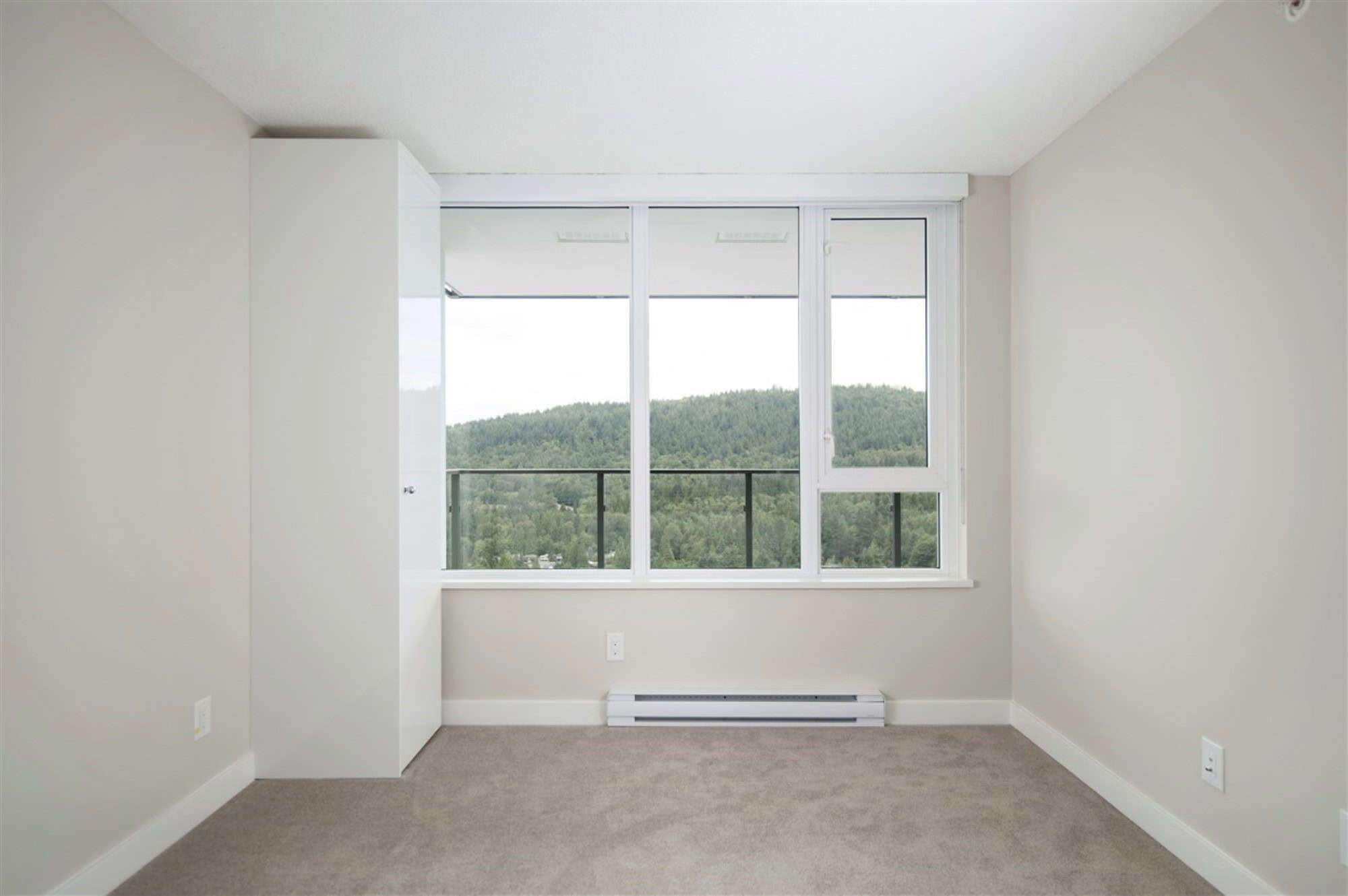 Modern apartment interior with large window overlooking green hills, ideal for Vancouver waterfront property and real estate investments in BC.