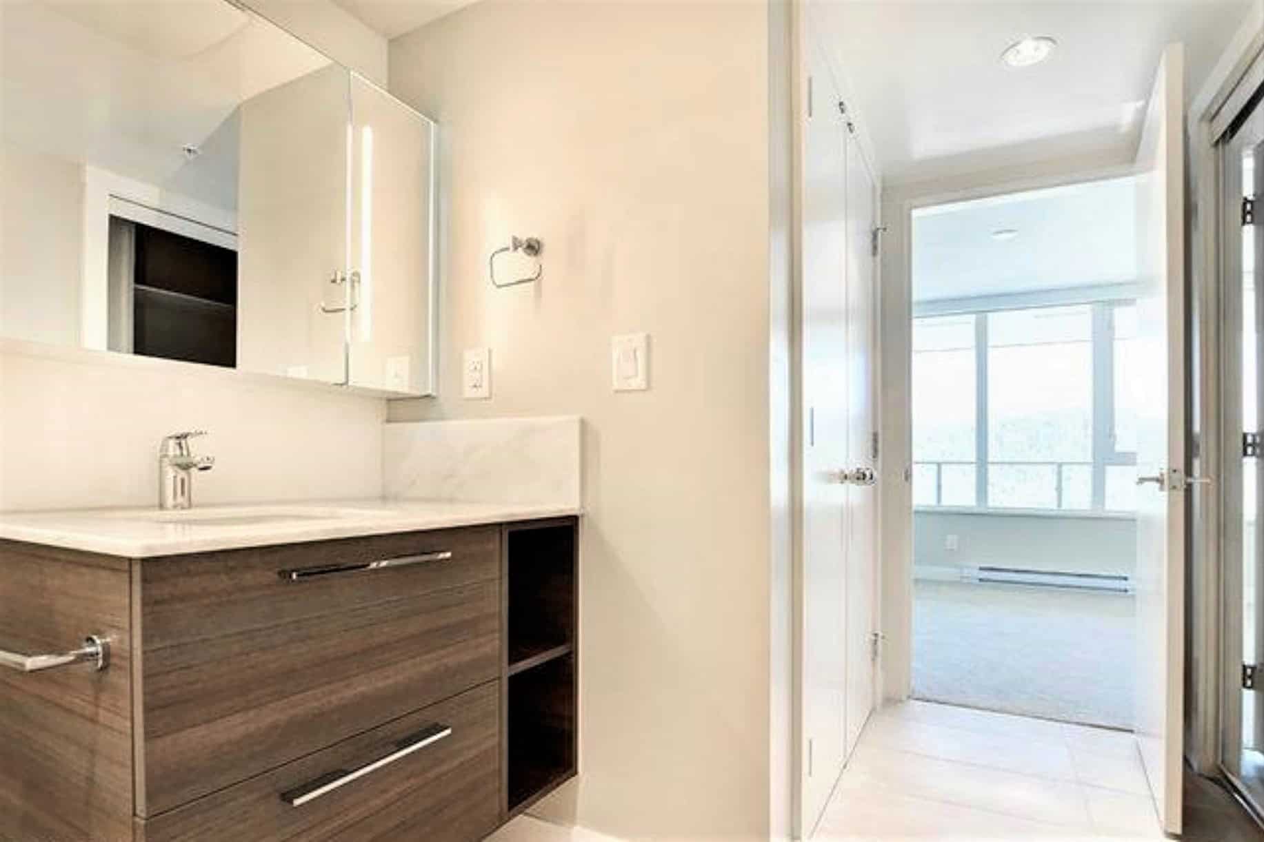 Bright modern laundry area with updated cabinetry and marble countertop, leading to a sunlit balcony with large windows, showcasing contemporary Vancouver condo living.