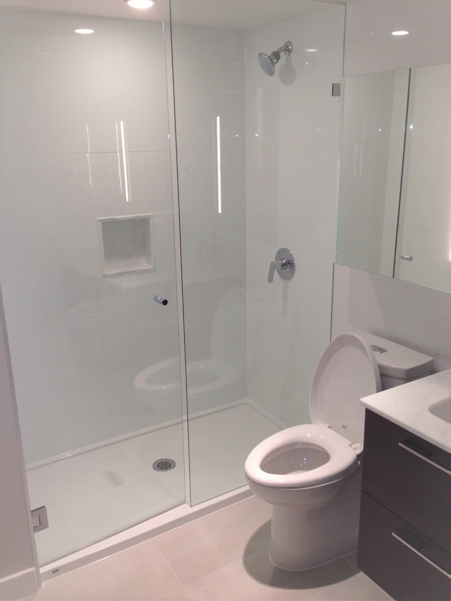 Modern white tiled bathroom with glass shower enclosure and contemporary fixtures – ideal for Vancouver Island homes.