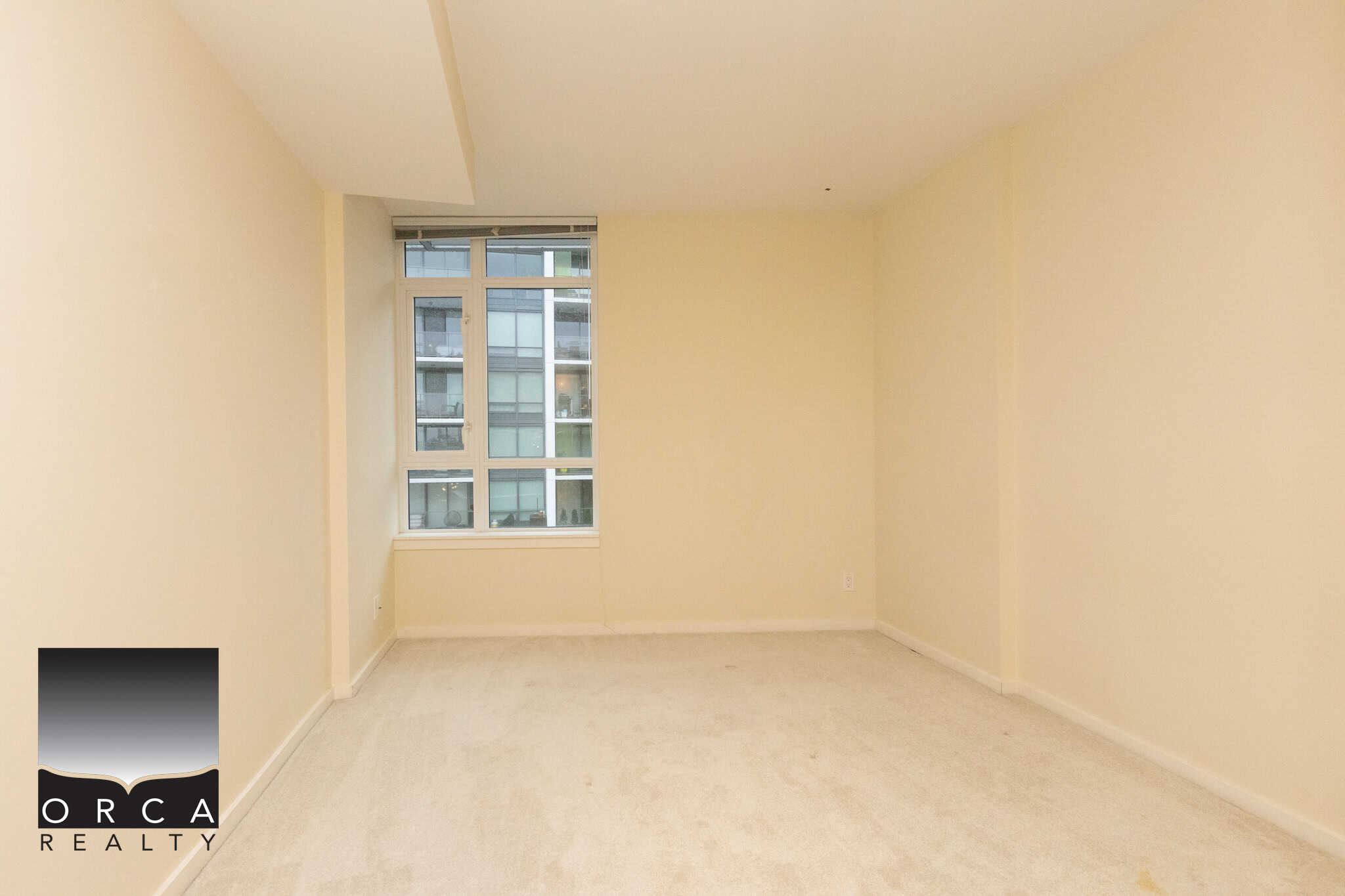13 (3) Bright modern apartment living room with large window, neutral paint, and plush beige carpet, perfect for comfortable urban living in Vancouver’s vibrant real estate market.