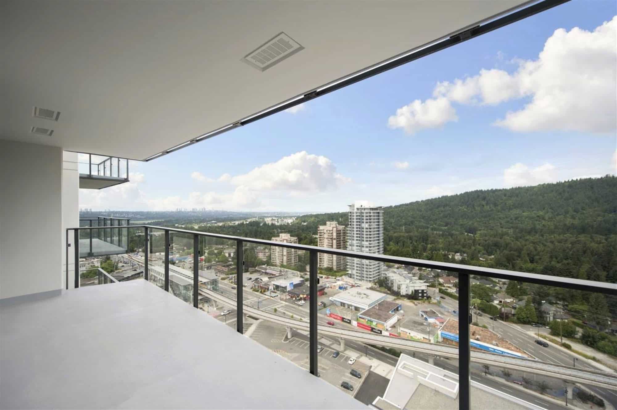 Panoramic view from a modern high-rise balcony showcasing cityscape, greenery, and urban infrastructure in a Vancouver-style setting, ideal for real estate buyers and investors.