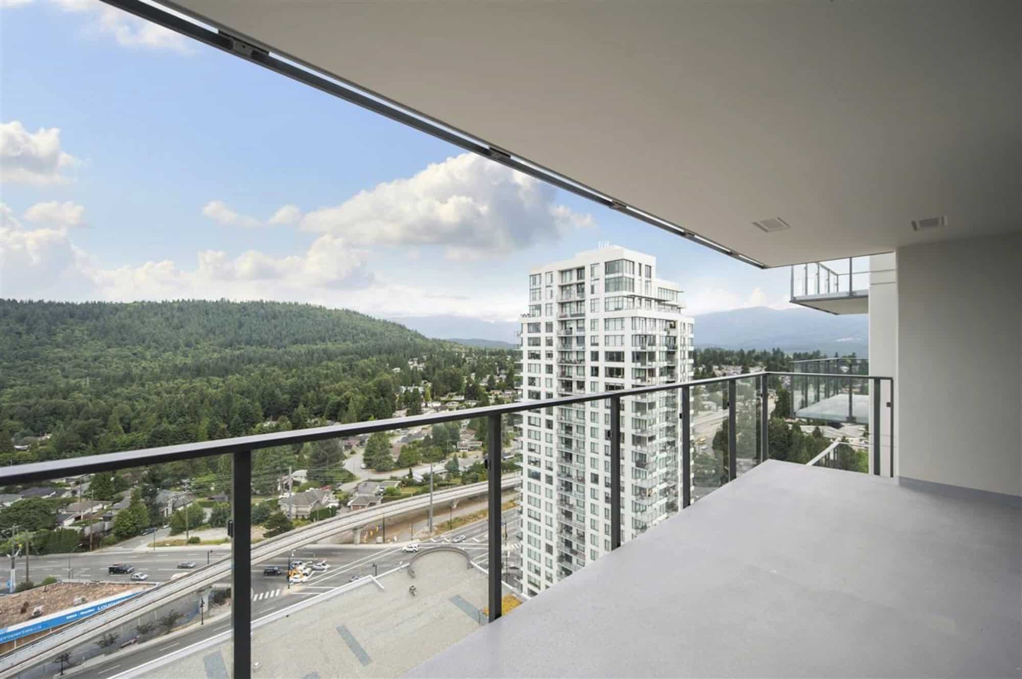 Stunning high-rise condo balcony view with cityscape and green hills in Vancouver, BC, showcasing luxury real estate and modern living spaces by Orca Realty Inc.