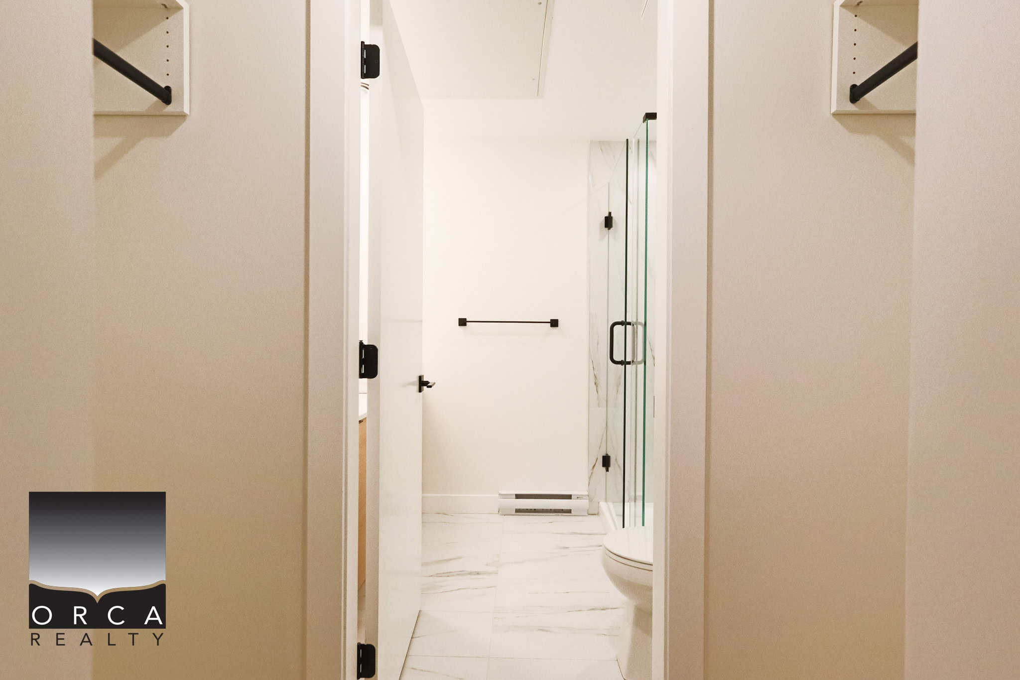 Modern bathroom with frameless glass shower and sleek white finishes, perfect for Vancouver real estate buyers seeking stylish, updated homes.