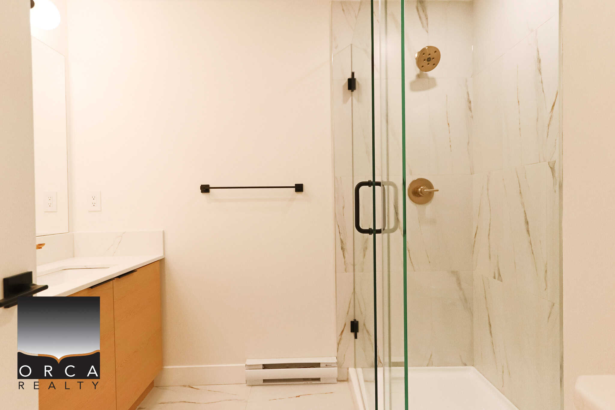 Modern bathroom with glass shower enclosure, marble tile accents, and contemporary fixtures, showcasing upscale real estate in Canada.