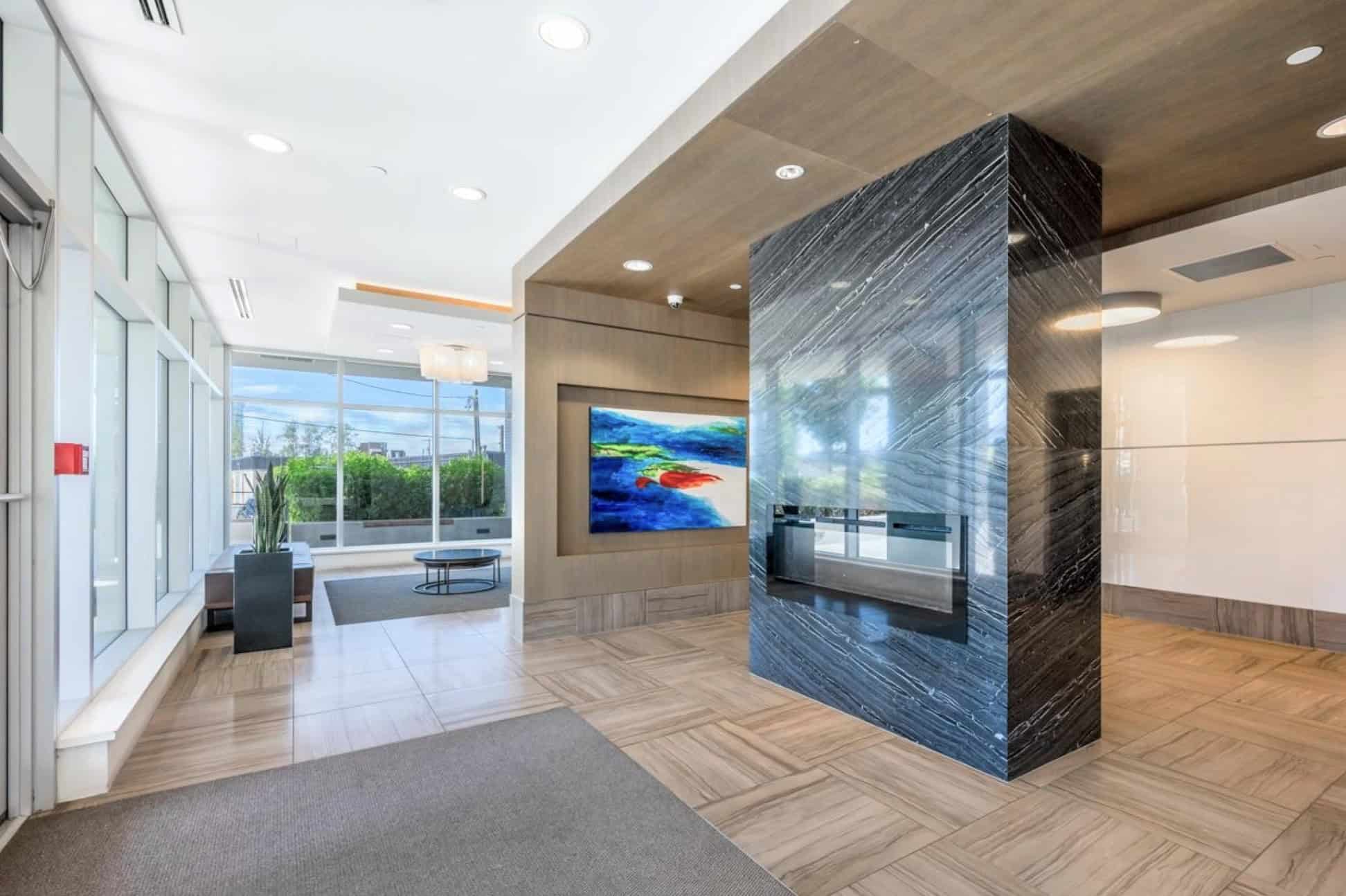 Contemporary office lobby with modern fireplace, sleek design, and large windows providing natural light, showcasing Orca Realty Inc.'s professional and inviting real estate services in Vancouver.