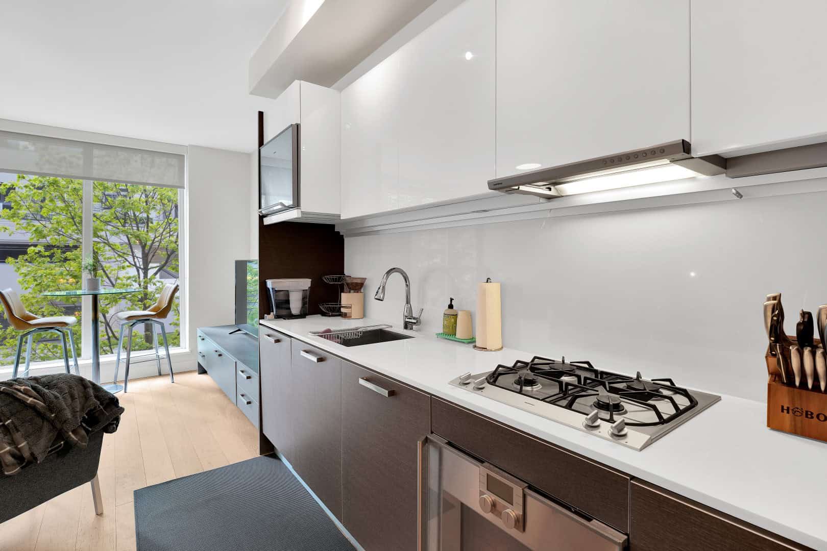 20 Modern kitchen with white and dark cabinetry, stainless steel appliances, large window with green views, ideal for Vancouver real estate buyers and investors.